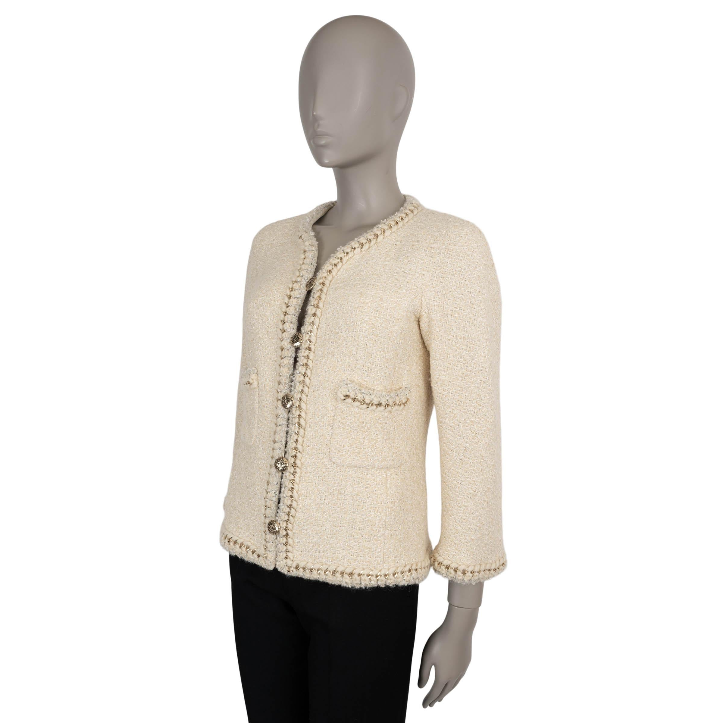 Cette veste 100% authentique de Chanel est une expression intemporelle du savoir-faire emblématique de la Maison. Confectionné en laine tweed beige et crème (100 %), il présente d'élégantes finitions tressées entrelacées de lurex argenté et d'une