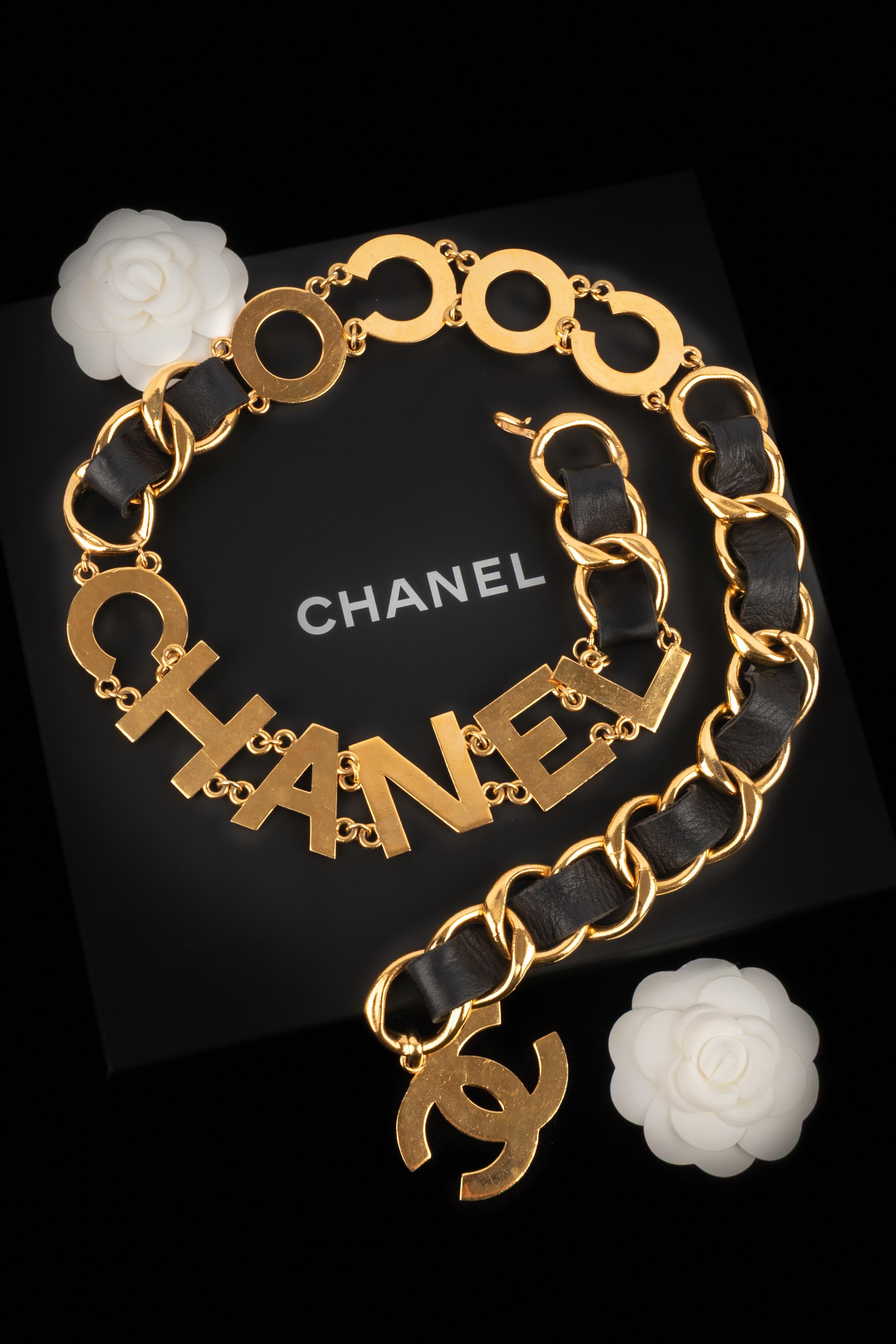 CHANEL - (Made in France) Golden metal chain belt partially interlaced with black lamb leather, interspaced with a 'Coco Chanel' pattern. Hook fastening. 1993 Spring-Summer Ready-to-Wear Collection  under the artistic direction of Karl