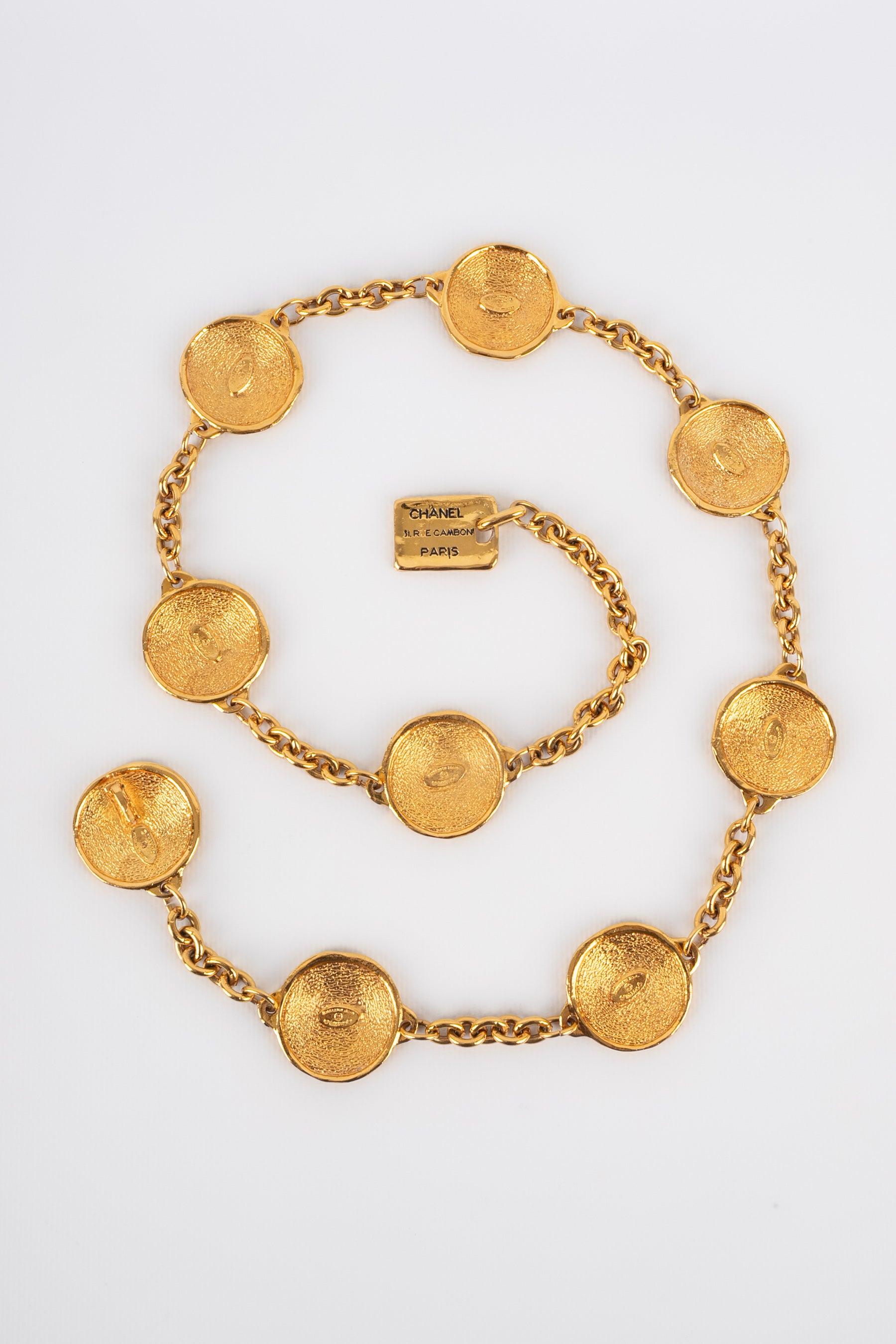 Chanel - (Made in France) Goldener Metallgürtel, bestehend aus Ketten und Medaillons, die Münzen darstellen. Schmuck aus den 1980er Jahren.
 
 Zusätzliche Informationen: 
 Zustand: Sehr guter Zustand
 Abmessungen: Länge: von 73 cm bis 85 cm
