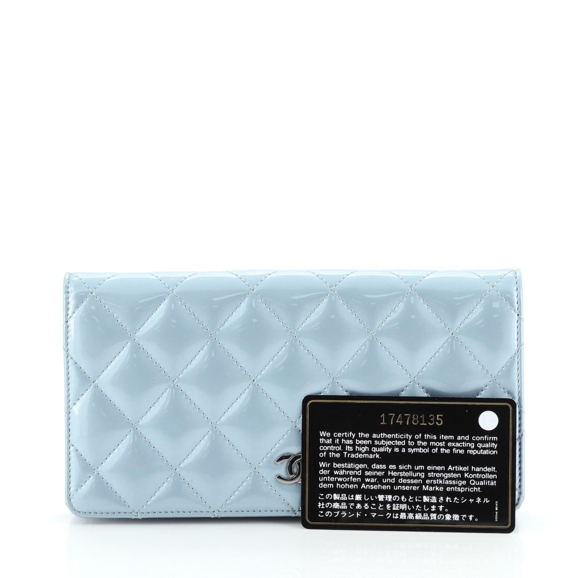 This Chanel Bi-Fold Wallet Quilted Patent, crafted from blue quilted patent leather, features CC logo at front and gunmetal-tone hardware. It opens to a blue leather interior with multiple card slots, zip pocket and slip pockets. Hologram sticker