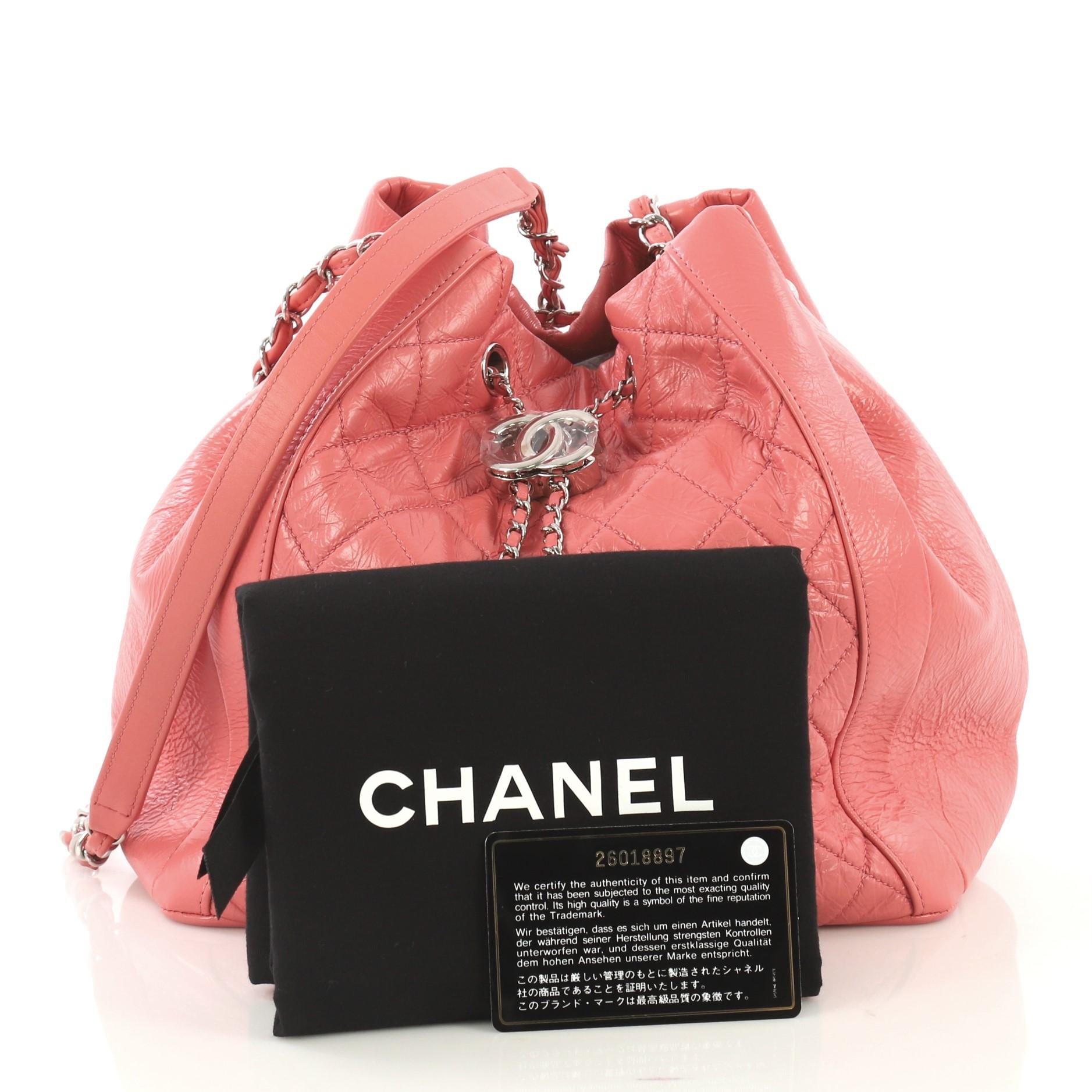 This Chanel Bi Vintage Drawstring Bucket Bag Quilted Crumpled Calfskin Medium, crafted in pink quilted crumpled calfskin, features woven-in leather chain strap with leather pad, and silver-tone hardware. Its drawstring closure opens to a pink fabric