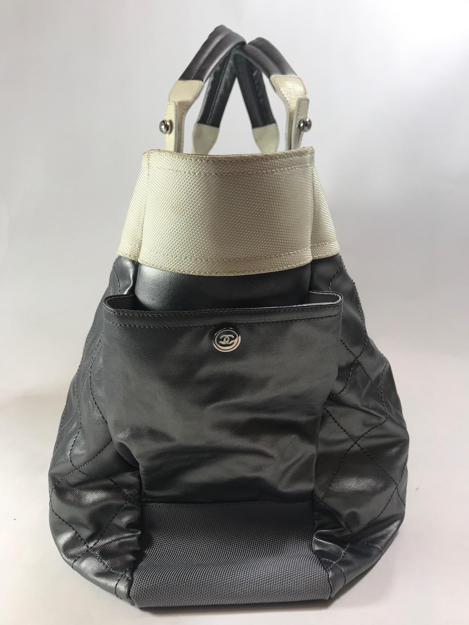 Neutral coated canvas. Silver metallic quilted coated canvas. Silver-tone hardware. Top zippered closure. Dual top handle. Side exterior pockets with button closure. Front zippered exterior pocket with 