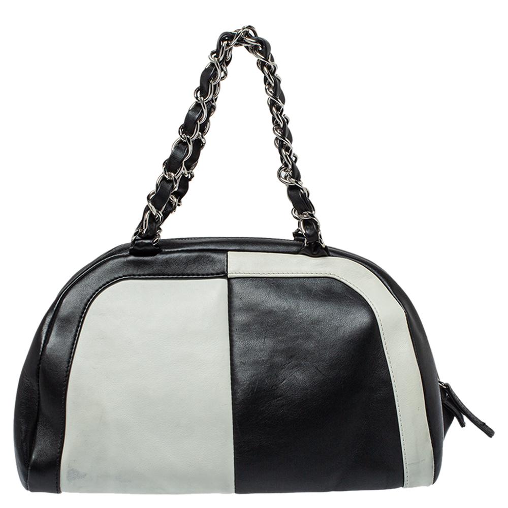 This sophisticated and spacious Bowling bag from Chanel is apt to carry your everyday essentials. Crafted in France from black and white leather, it features silver-tone hardware detailing. The bag exhibits a CC logo at the front, twin entwined