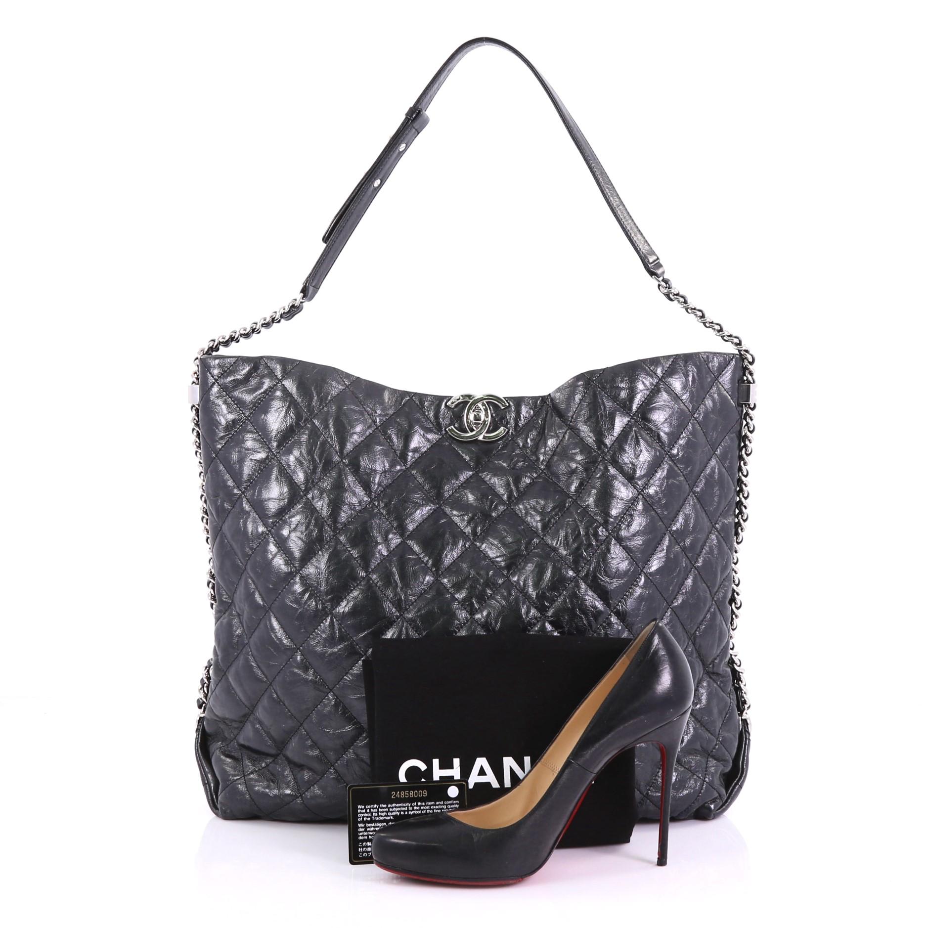 This Chanel Big Bang Hobo Quilted Metallic Aged Calfskin Large, crafted from black quilted metallic aged calfskin, features woven-in leather chain link strap with leather pad and silver-tone hardware. Its CC turn-lock closure opens to a black fabric