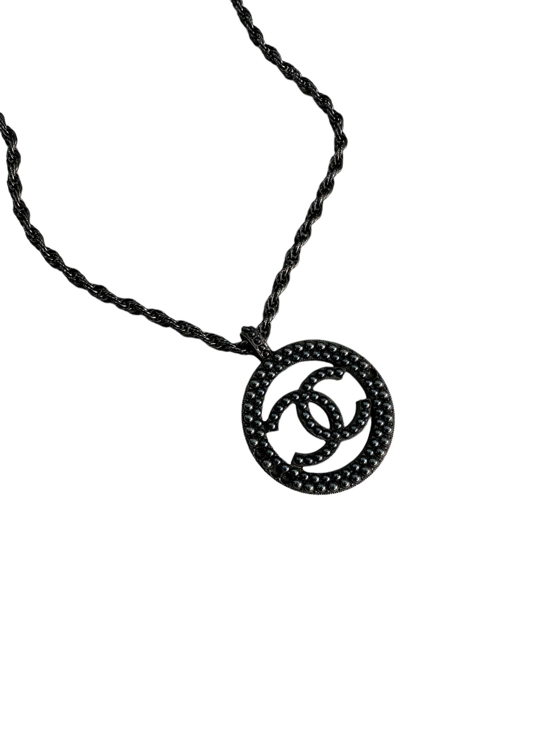 Chanel signed necklace, Big Logo model, made of gray matte with small gray pearls on the front. Equipped with a hook closure, it is in good condition, with some missing beads.

