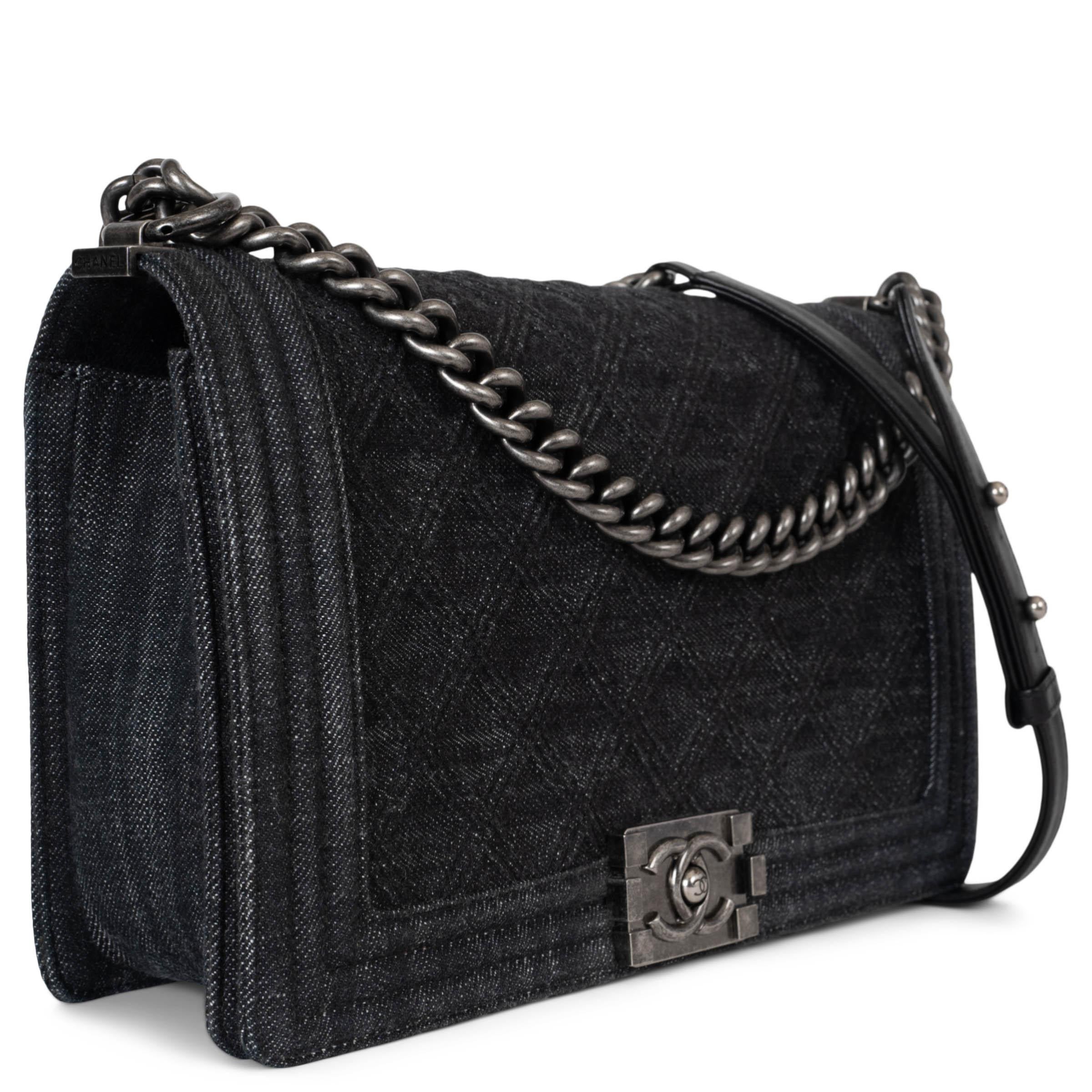 Este bolso bandolera con solapa Boy Large 100% auténtico de Chanel en tejido vaquero negro con herrajes de rutenio (tono plateado antiguo) es una pieza atrevida pero atemporal. Con una doble solapa acolchada y una correa de piel y cadena, encarna el