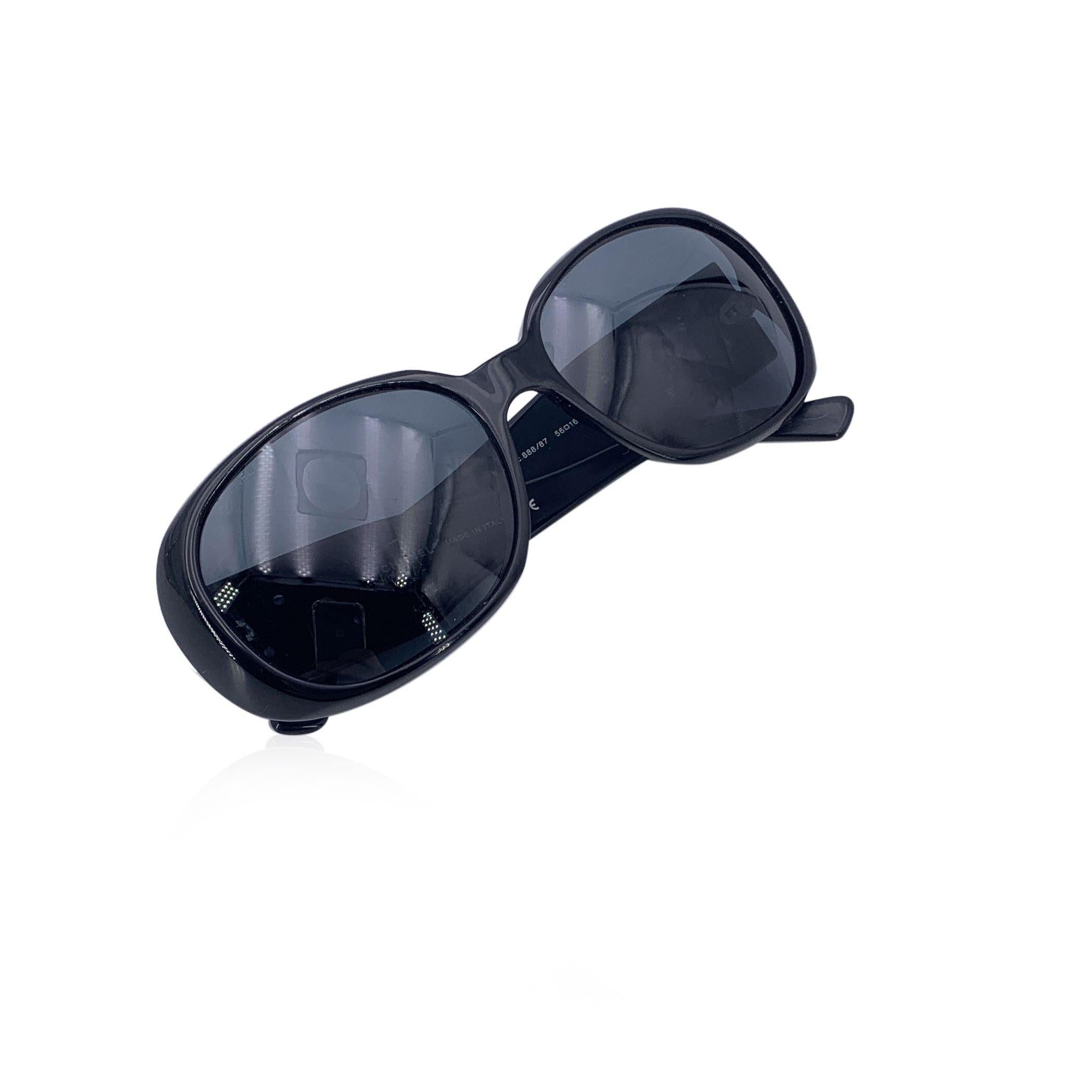 Lunettes de soleil rectangulaires Chanel mod. 5113 - c.888/87. Elles sont dotées d'une monture en acétate noir avec des fleurs de camélia noires et un petit logo CC sur les branches. Lentilles grises d'origine. Mod & refs : mod. 5113 - c. 888/87 -
