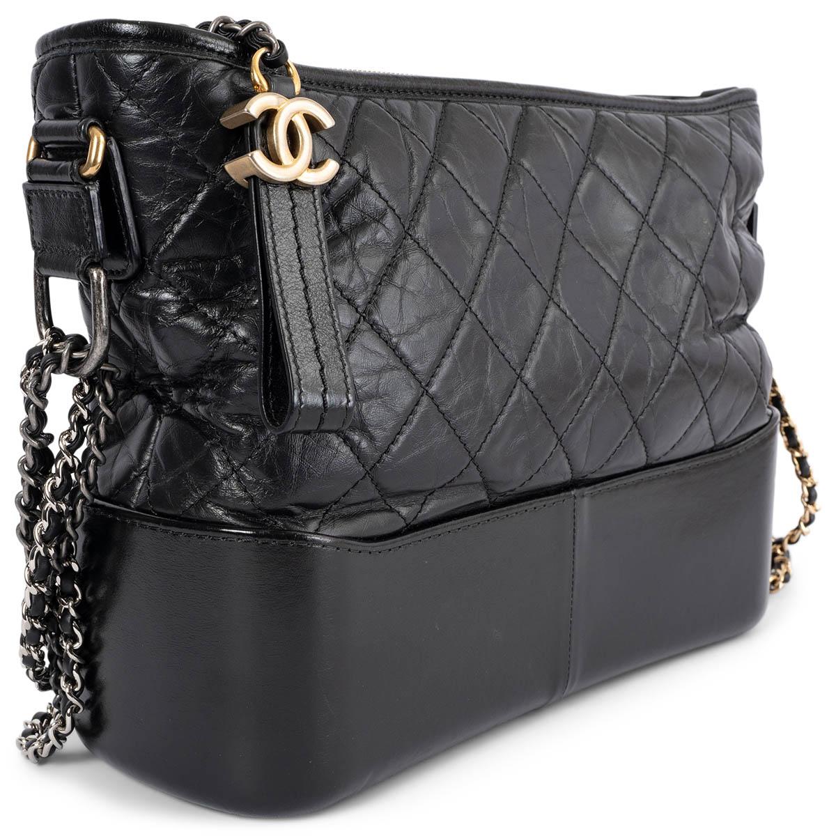 100% authentic Chanel Gabrielle Medium Hobo Bag in black aged calfskin featuring double chain shoulder-strap in gold-tone, silver-tone & ruthenium-finish metal. Opens with a CC zipper on top and is lined in red grosgrain fabric with one zipper