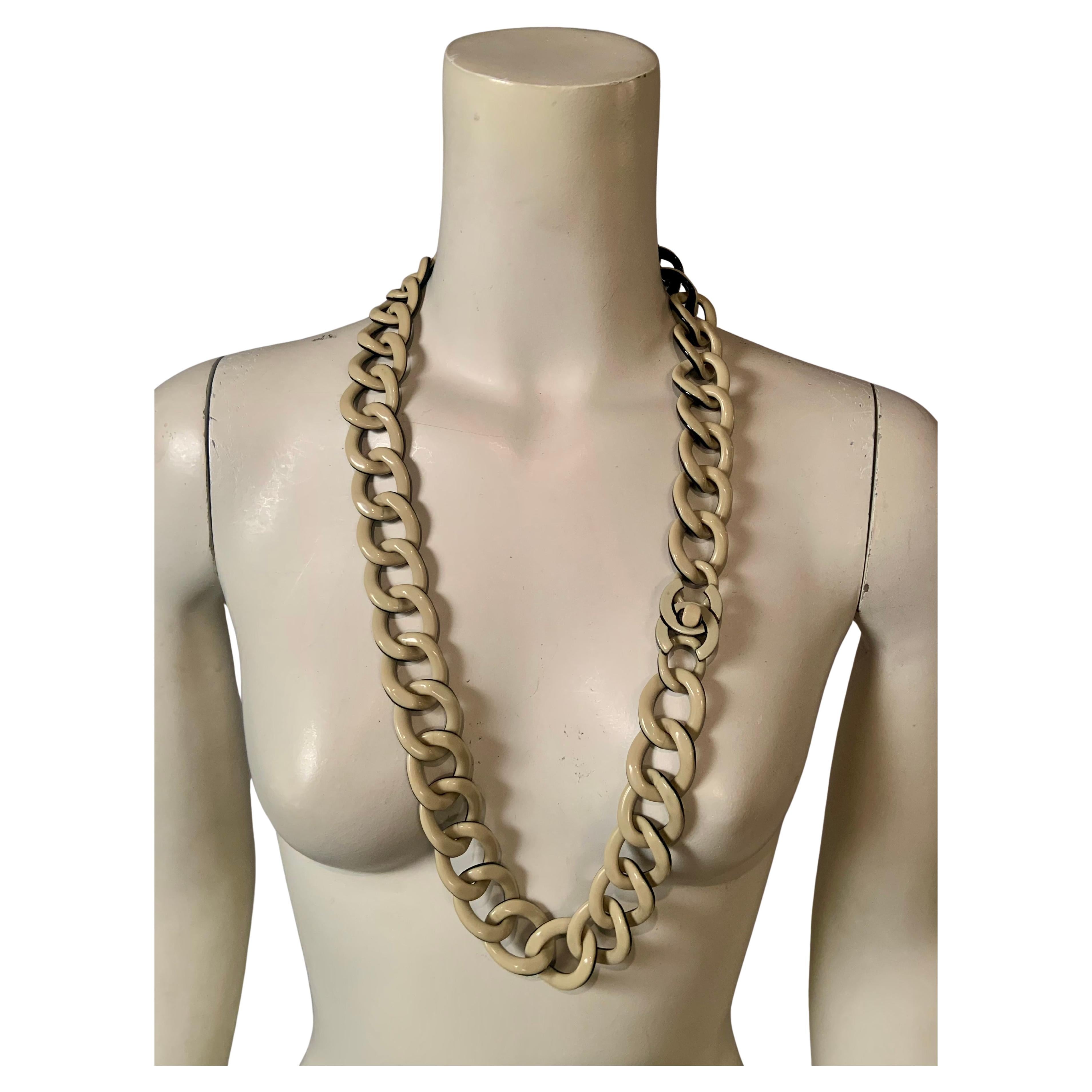 Questa collana vintage con logo doppia C di Chanel, composta da maglie a cordoncino in resina color crema e nera, è un pezzo che può essere indossato in diversi modi. Il lato 