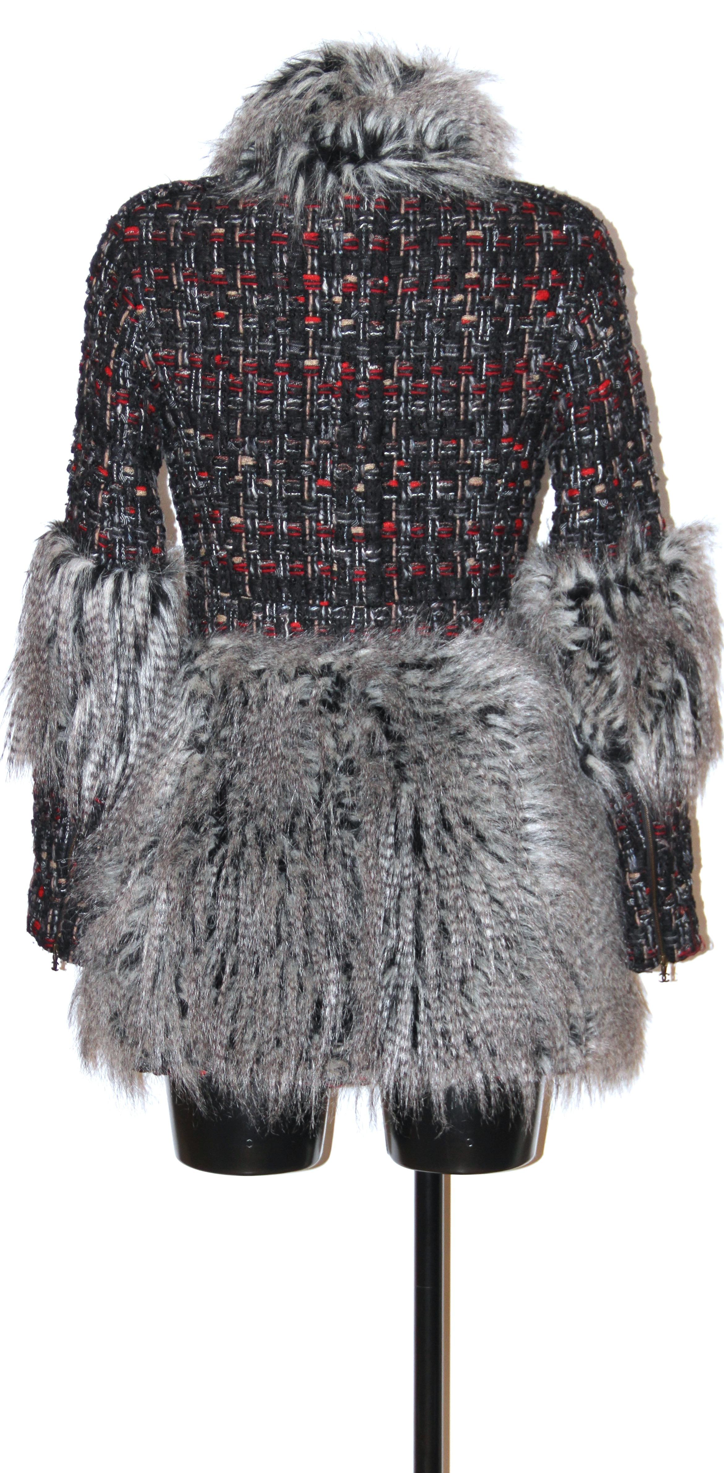 This pre-owned very interesting long jacket from Chanel is made of a black and red multicolored tweed.
Grey faux-fur is woven into the tweed, forming deep pelmets on the lower half of the jacket as well as aroung the cuffs and the collar.
A hidden