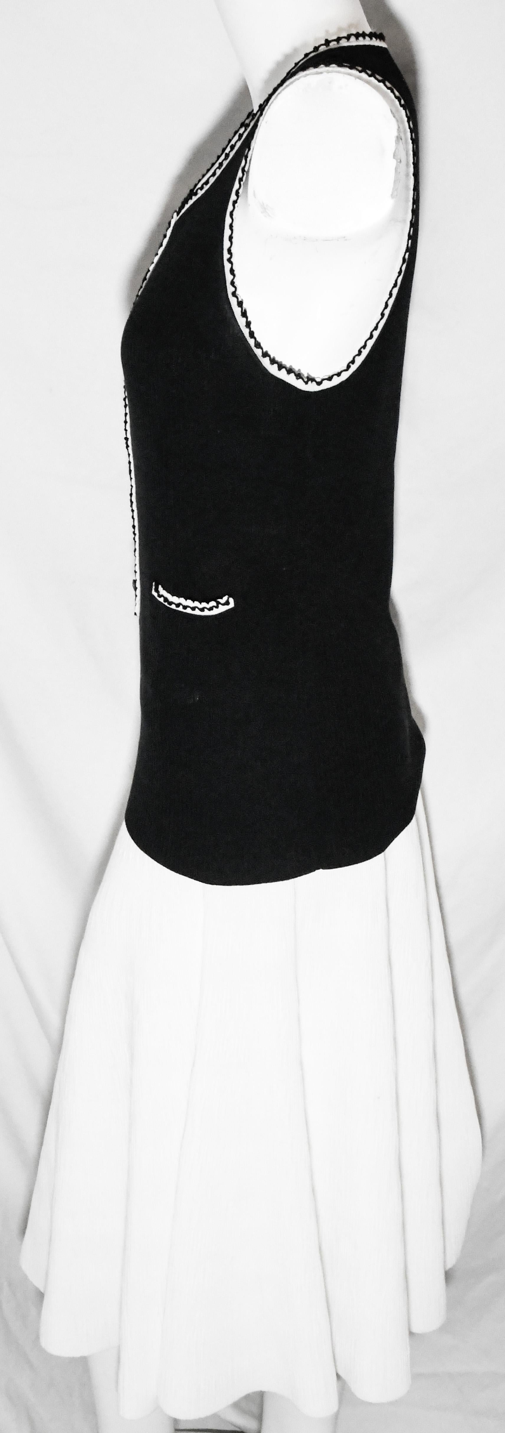 Chanel black sleeveless top with white trim around neckline, arm openings and front placket.  Five Chanel CC logo buttons,  also decorates the front placket.  This long t-shirt style top contains 2 small front patch pockets.   The top is not lined. 