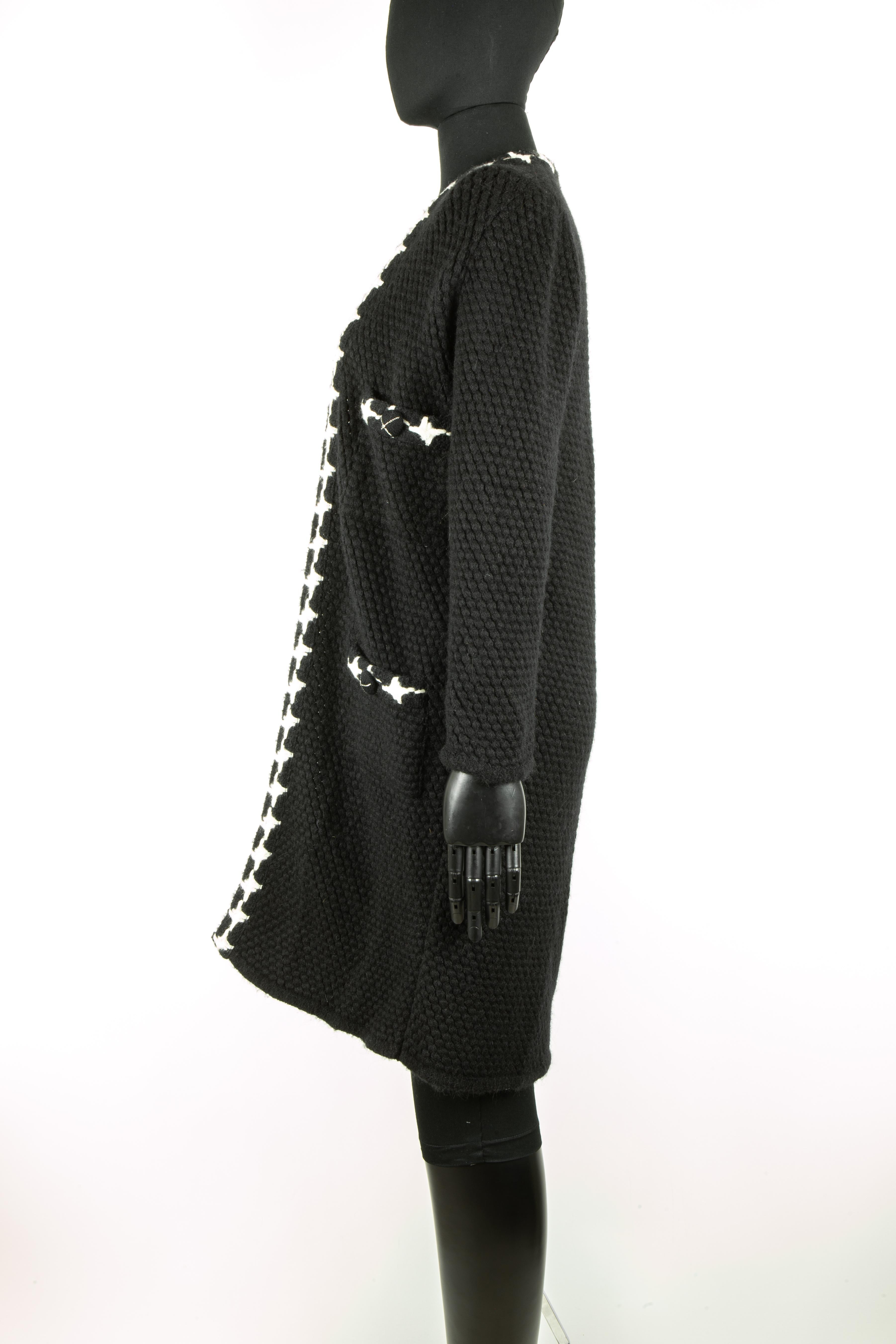 A beautiful Chanel black cashmere knitted coat with striking contrasting white trim stretching across the neckline, centre front and across all four pockets. This coat also features large buttons covered in the same black cashmere and adorned with a