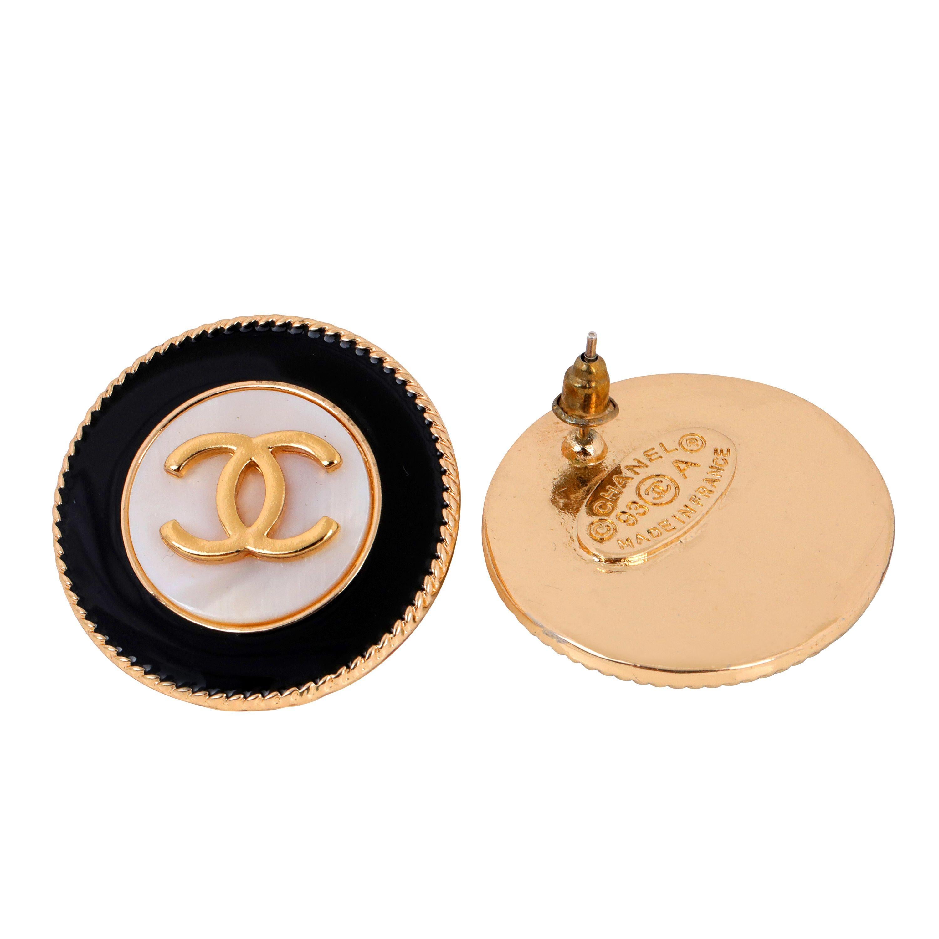 Diese authentischen Chanel Black and White Pearlized Pierced Earrings sind in ausgezeichnetem Vintage-Zustand aus der Fall 1993 Collection.   Runde Knopfohrringe mit goldfarbener Umrandung, zentralen, ineinandergreifenden CCs und einer perlweißen