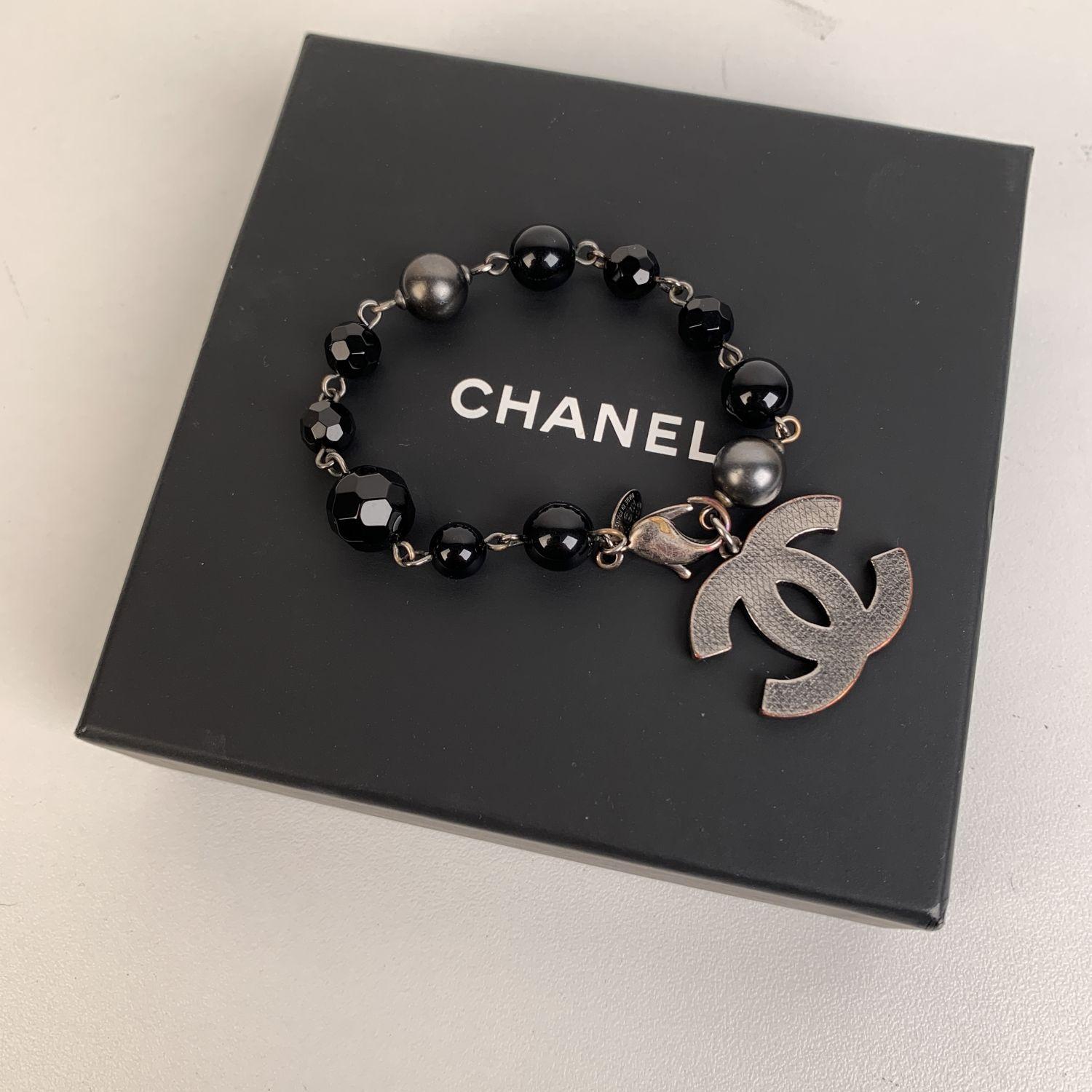 Stylish Chanel silver metal bracelet with black glass beads and CC - CHANEL logo charm. CC logo width is about 1.25 x 0.95 inches. Lobster closure. Total lenght: 7 inches - 17,7 cm. 'CHANEL A12 - CC - V - Made in France' oval tag

Condition

B -