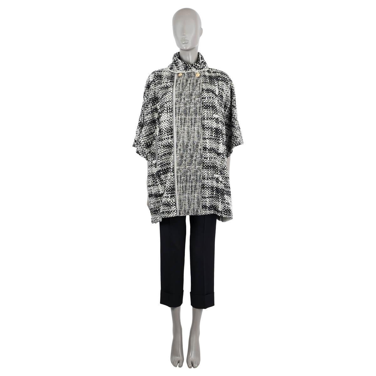 100% authentic Chanel tweed jacket in black and beige cotton (with 5% polyester). Features a shawl collar, short sleeves and a placket on the front with two gold head buttons. Buttons on the side for a poncho like effect. Unlined. Has been worn and