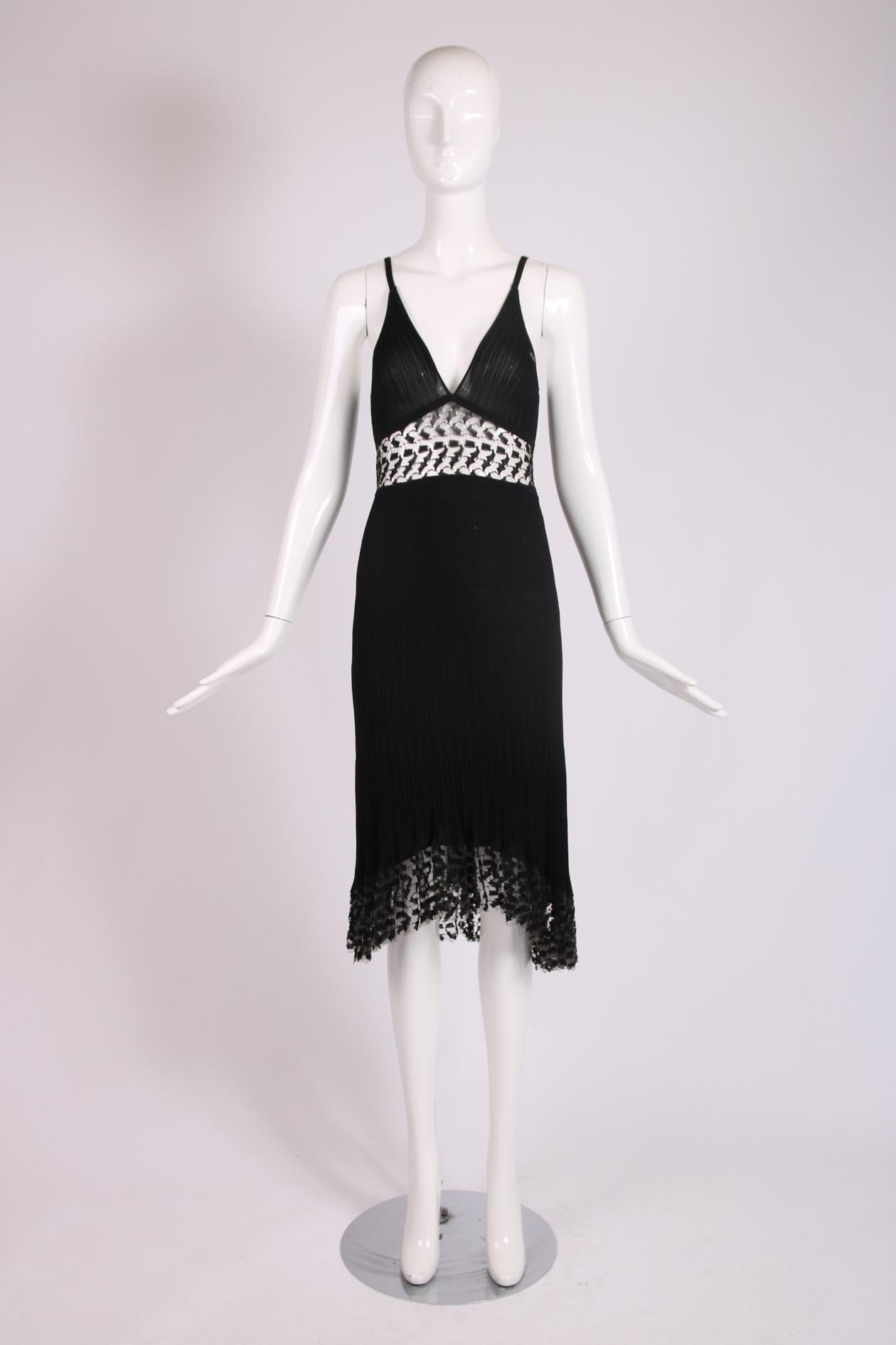 Chanel 2006 Cruise collection fitted black ribbed stretchy dress featuring a deep V-neckline and transparent lace cutouts design motif below the bust and at the flounced high-low hem. Skirt is lined at the interior. Fabric is a viscose, polyamide