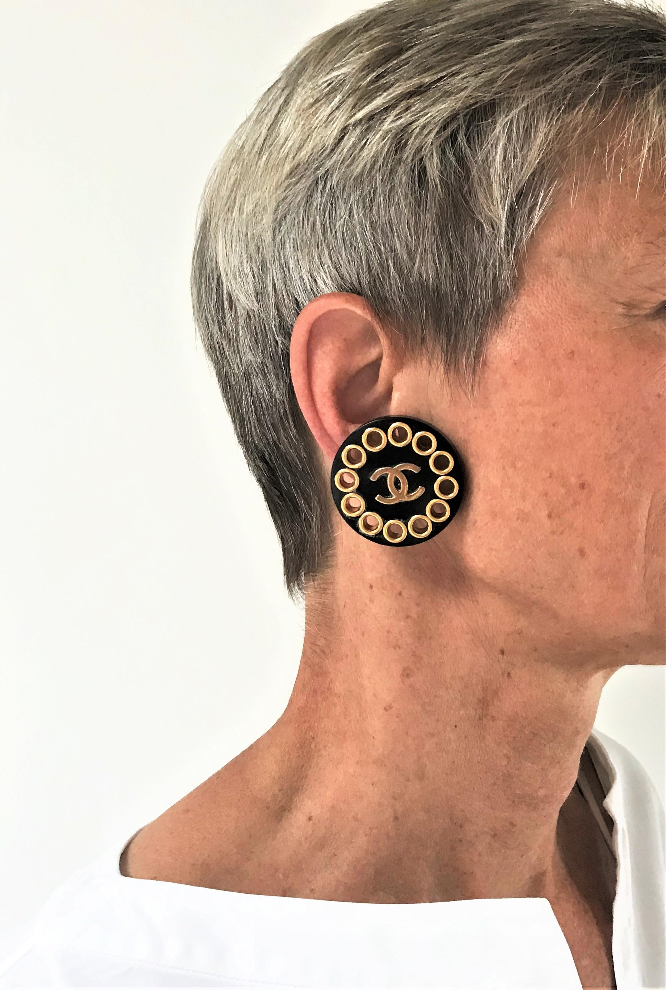 A bold black Chanel round ear clip with gold plated CC and holes all around. Signed on the back with 2CC8
Diameter 4 cm / 1,57