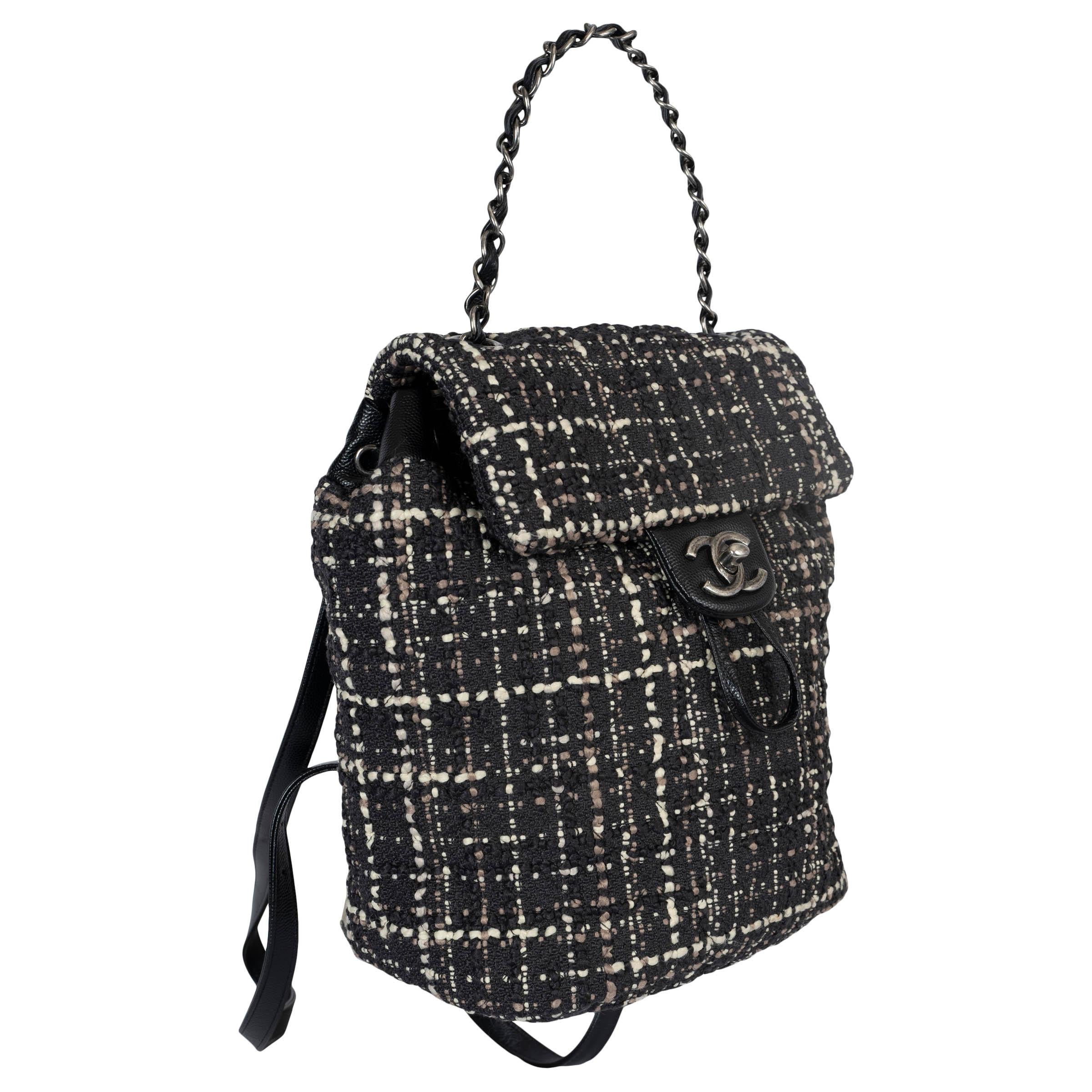 Mochila Chanel Pequeña Urban Spirit 100% auténtica en tejido de tweed negro, blanco y topo y piel Caviar negra. Lleva tirantes de cuero con eslabones de cadena en tono plata envejecida. Se abre con una solapa con cierre giratorio con el logotipo CC