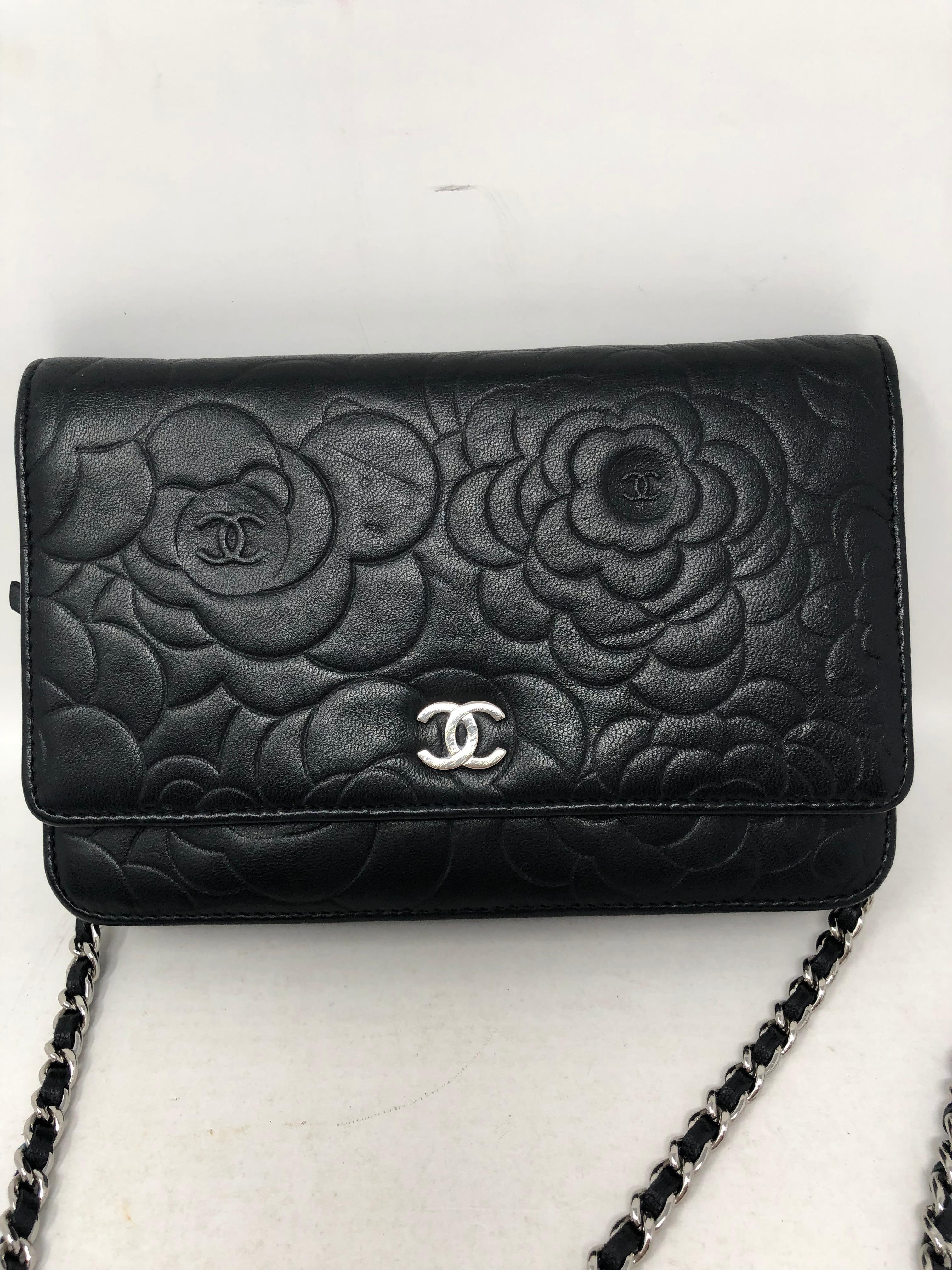 Chanel Black Camelia Wallet On A Chain. Silver hardware. Can be worn as a clutch or crossbody. A few indentations from wear. Good condition otherwise. Soft lambskin leather. Guaranteed authentic. 