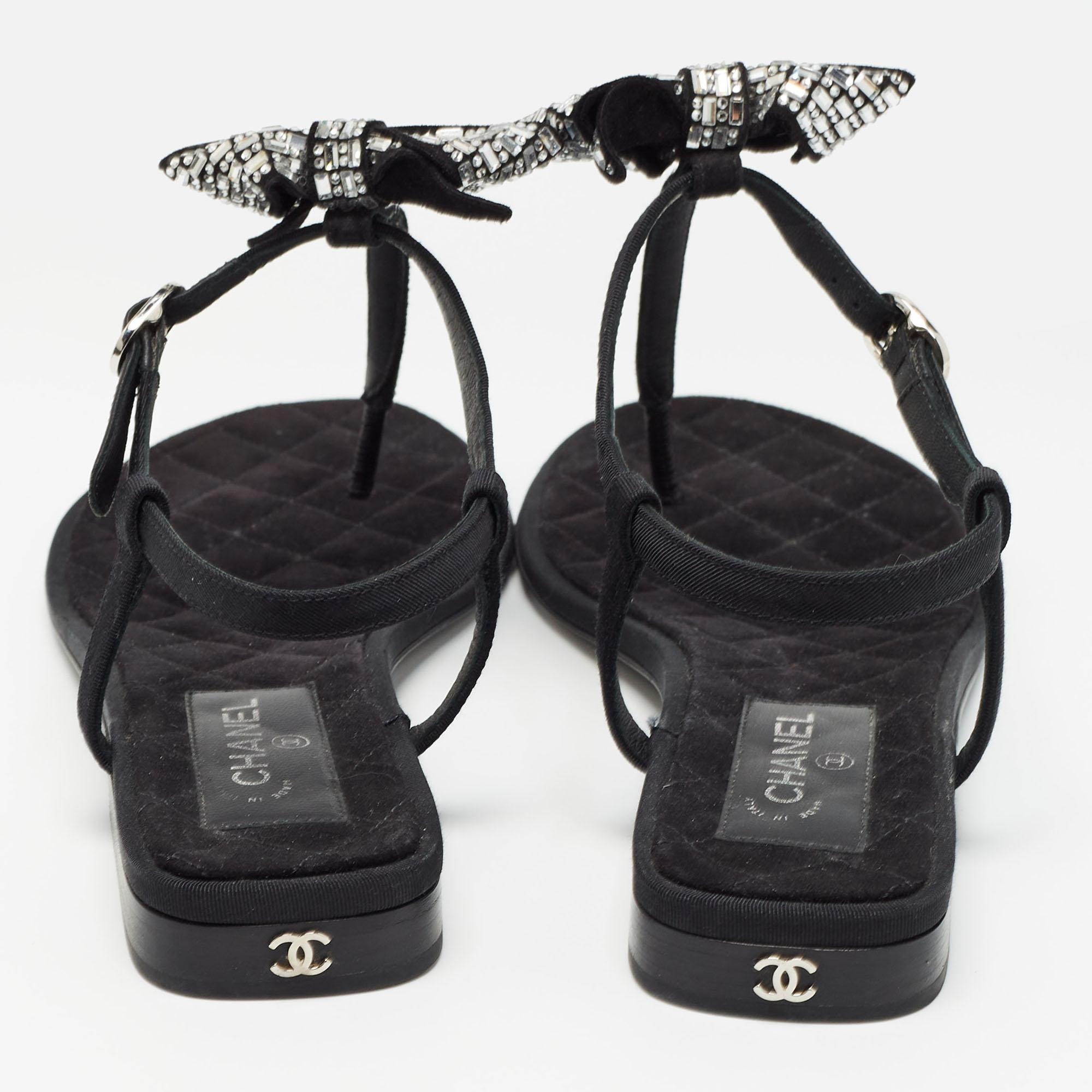 Sehen diese Sandalen von Chanel nicht absolut königlich und prächtig aus? Diese fabelhaften schwarzen Sandalen verzaubern mit ihrem Canvas-Außenmaterial und der mit Wildleder gefütterten Innensohle. Mit Verzierungen auf dem Oberteil sind sie jeden
