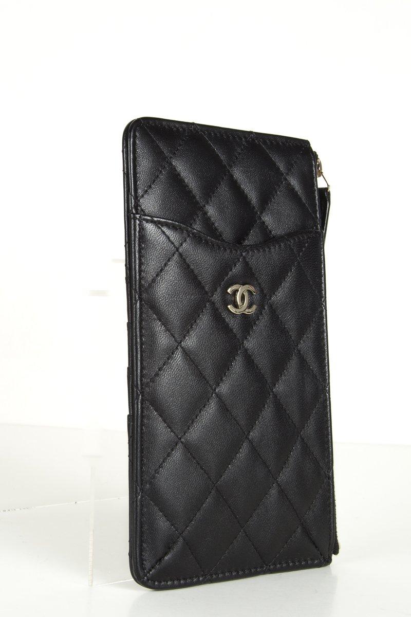 Chanel quilted lambskin leather in black featuring a gold Chanel CC logo at front, an exterior pocket, card slots, and a top zipper that opens to a burgundy fabric interior. Chanel date code detached. Includes dustbag.