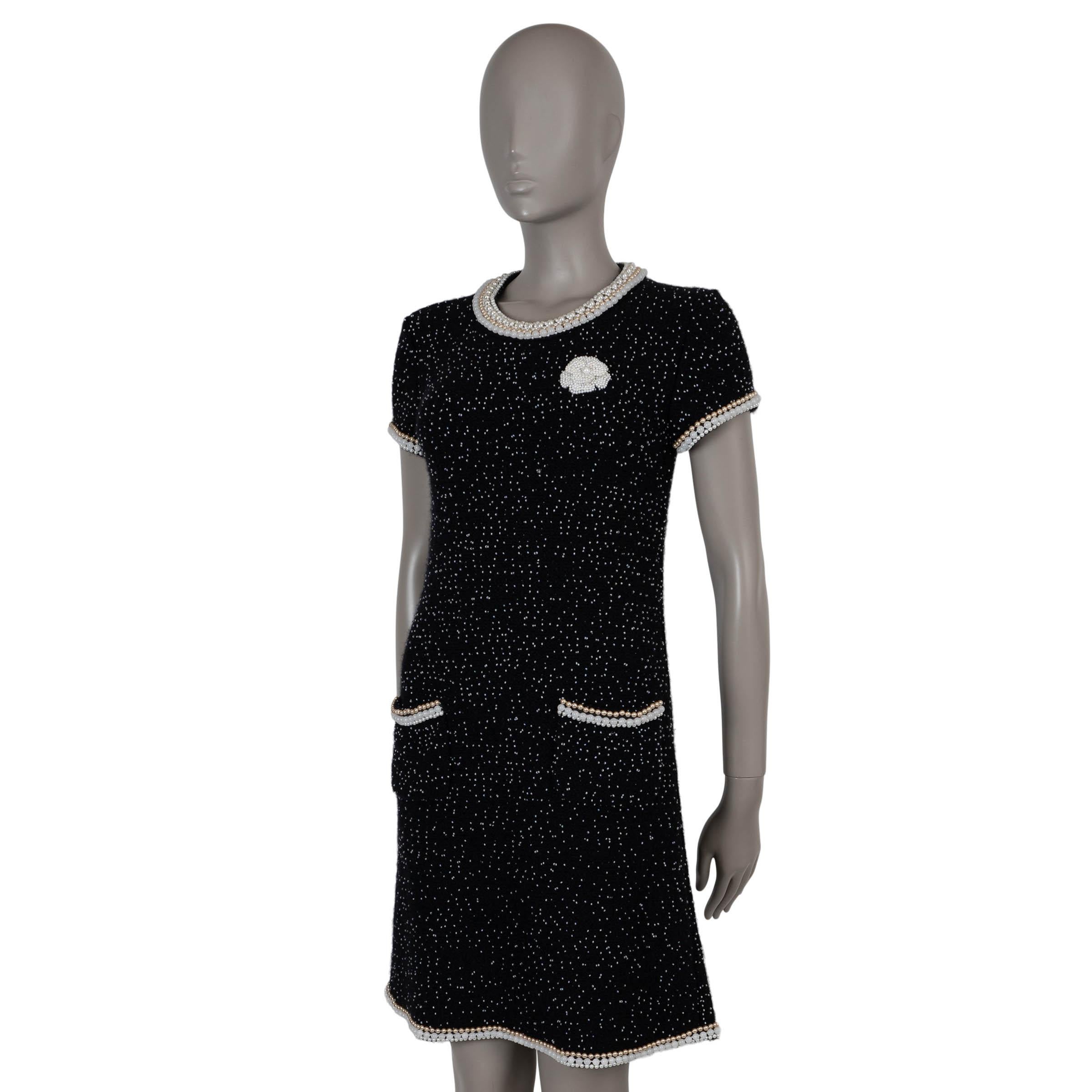 This 100% authentic Chanel knit dress in black cashmere (40%), wool (35%), cotton (15%), and nylon (10%) is adorned with all-over mini pearls and a signature pearl camellia at the chest. Featuring a relaxed silhouette with short sleeves and a round