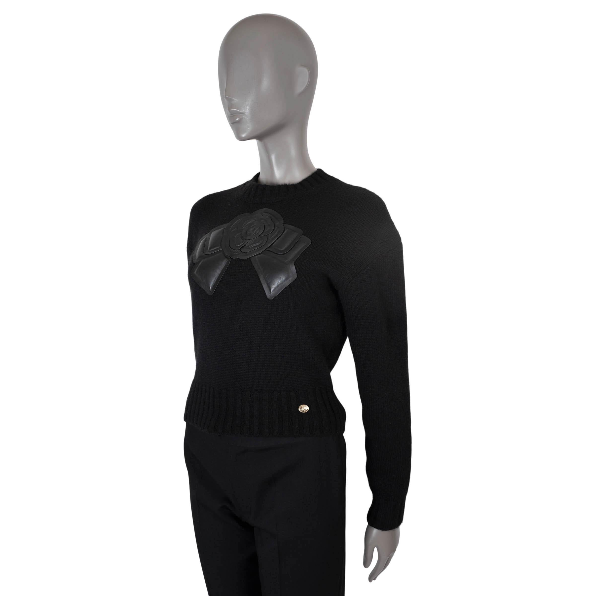 Pull court en cachemire noir (100%) authentique de Chanel. Doté d'un col et d'un ourlet en tricot côtelé, d'un nœud Camélia en cuir d'agneau et d'un bouton logo à la taille. A été porté et est en excellent état.

2020 Automne/Hiver