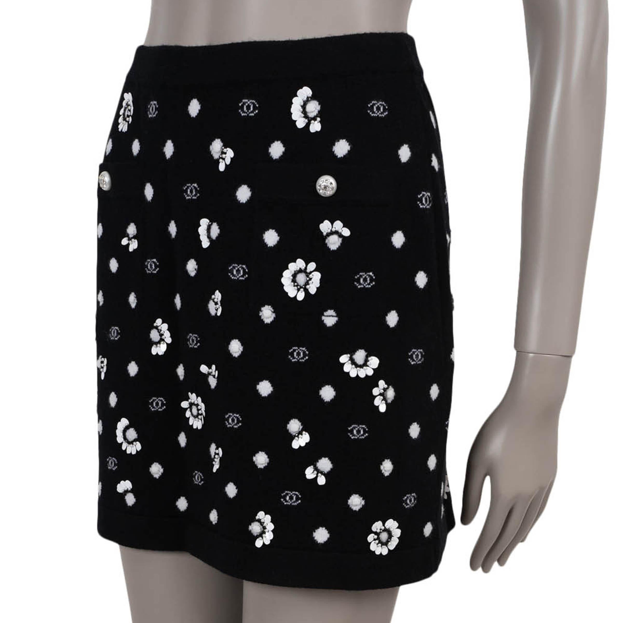 This 100% authentic Chanel knit skirt is an extraordinary runway piece, crafted in black cashmere with an all-over white CC and polka-dot jacquard. Intricate floral embellishments made from cream flat sequins and black beads elevate its couture