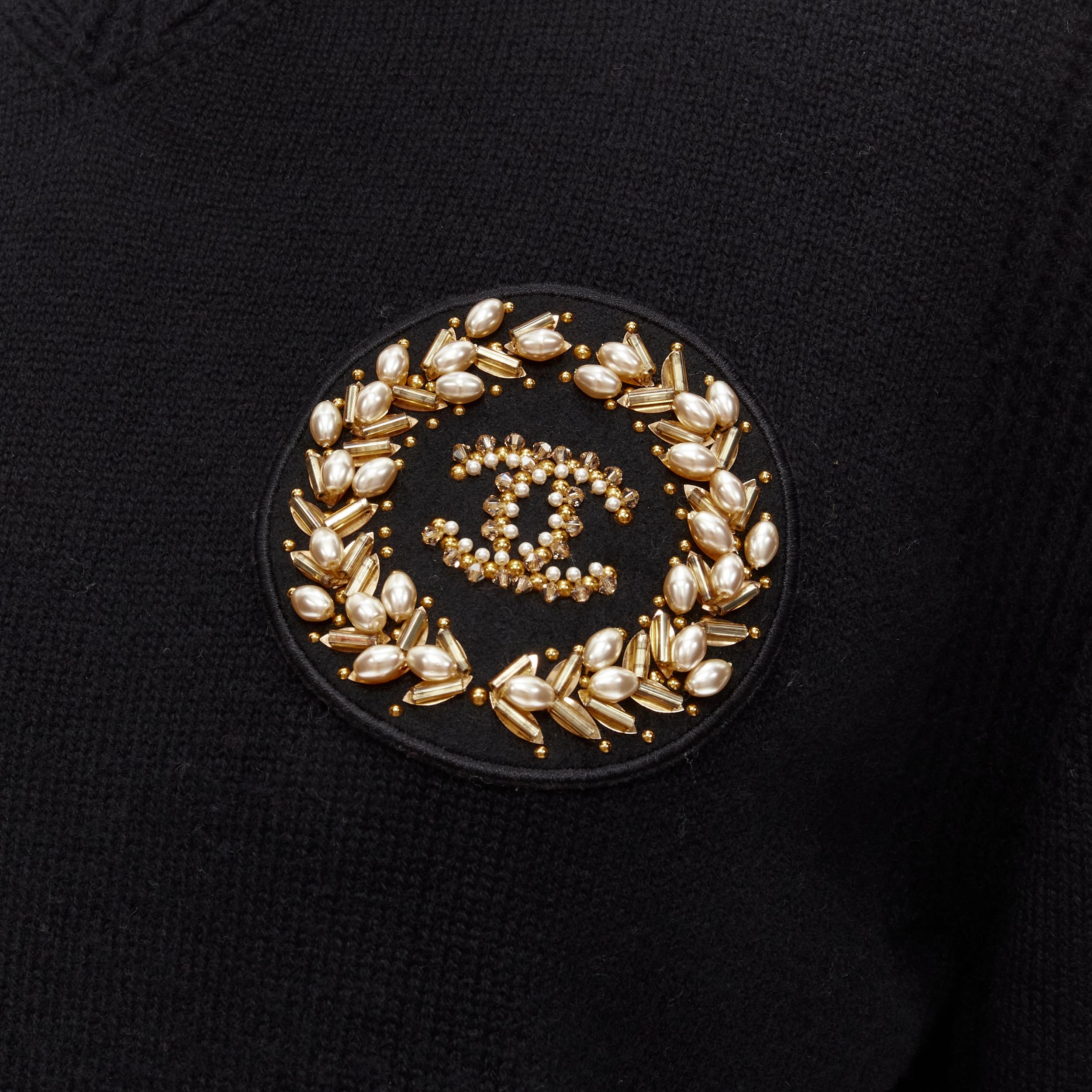 CHANEL black cashmere blend gold bead pearl CC embellished badge sweater FR42  L
Brand: Chanel
Material: Cashmere
Color: Black
Pattern: Solid
Extra Detail: Ribbed detailing at collar and along shoulder seams. Gold-tone metal and pearl bead