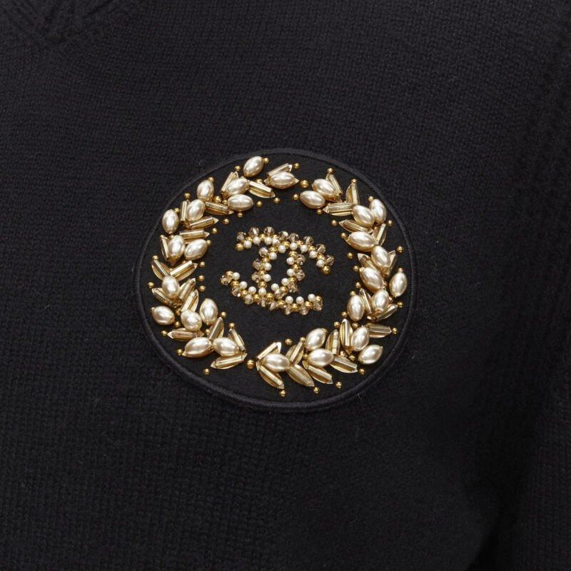 CHANEL black cashmere blend gold bead pearl CC embellished badge sweater FR42  L
Reference: KNLM/A00089
Brand: Chanel
Designer: Karl Lagerfeld
Model: P64669K60693
Material: Cashmere, Blend
Color: Black, Gold
Pattern: Solid
Extra Details: Ribbed