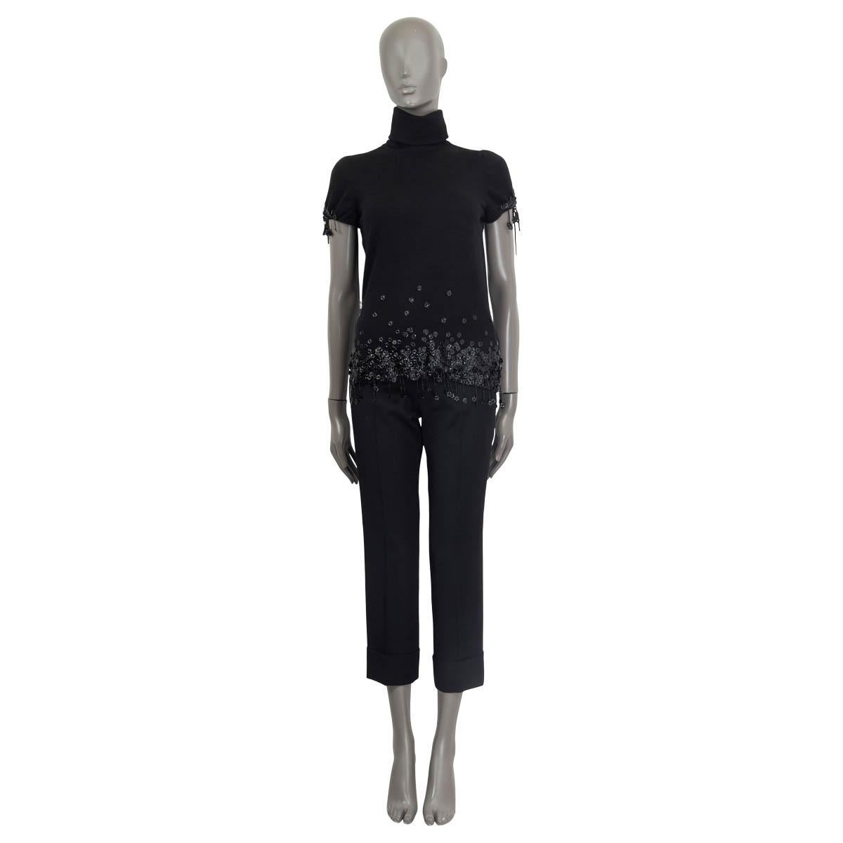 100% authentic Chanel short sleeve top in black cashmere (100%). Embellished with pearl fringes and black flowers. Features a turtleneck and opens with eight 'CC' buttons on the back. Unlined. Has been worn and is in excellent