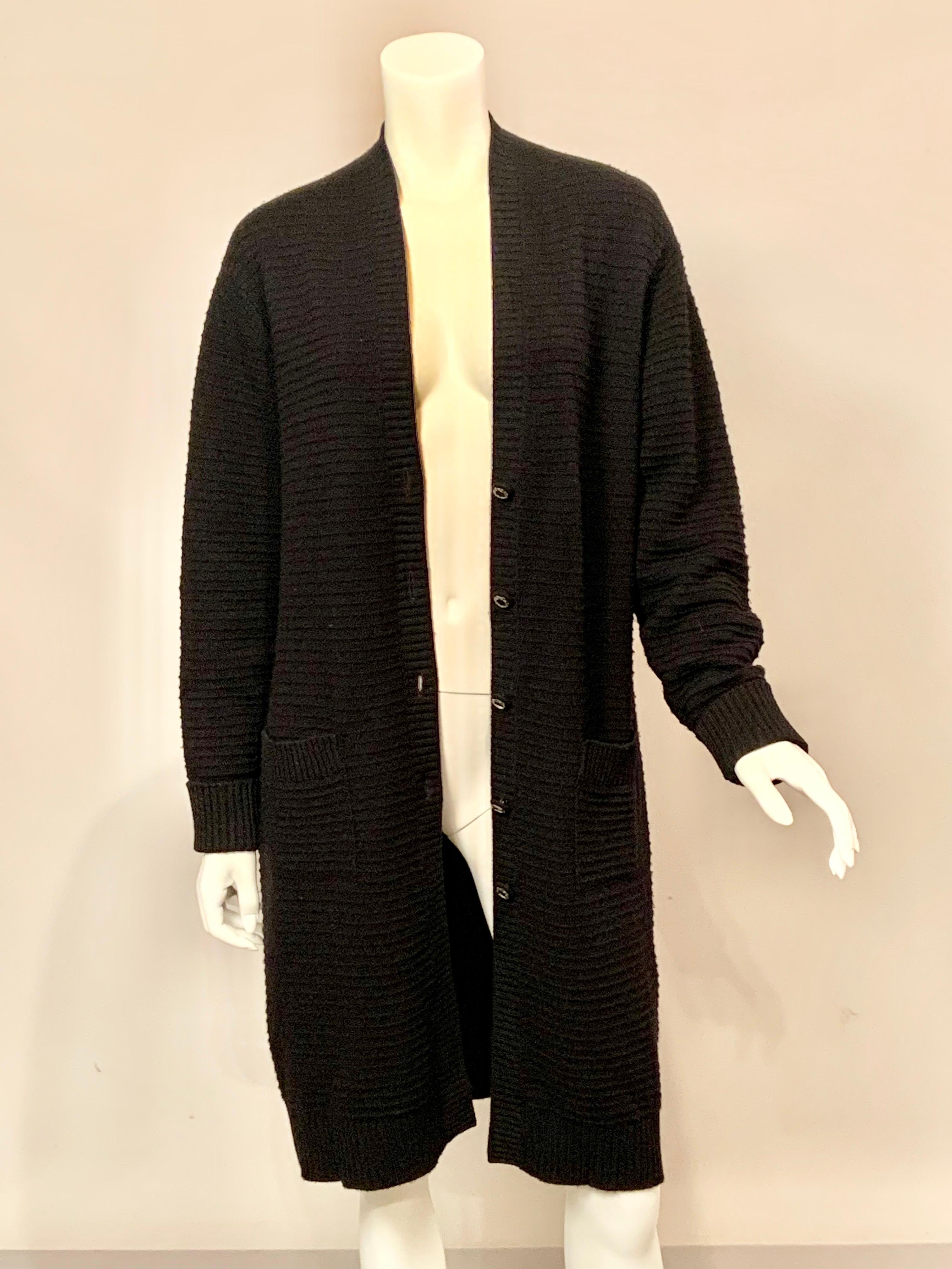 Soft black cashmere in a ribbed knit design is used for this timeless long 1920's inspired cardigan sweater designed 
by Karl Lagerfeld.  It has a V neckline, five Chanel buttons at the center front, and two generous patch pockets. It is in