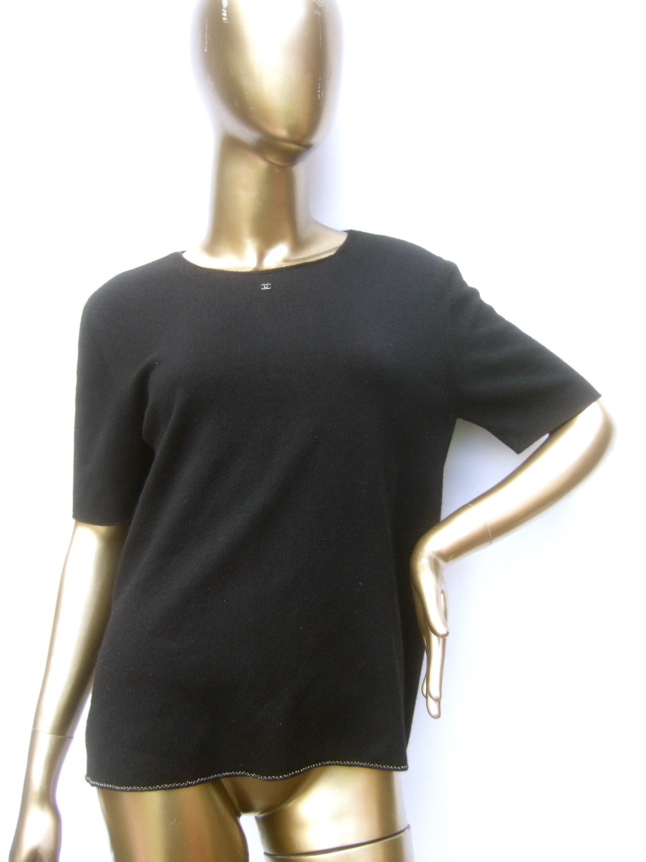 Chanel black cashmere silk blend short sleeve sweater c 1990s

The luxurious sweater is adorned with Chanel's subtle C.C. initials at the center neckline in tiny silver metal letters
The exterior hemline is designed with a restrained pewter-tone