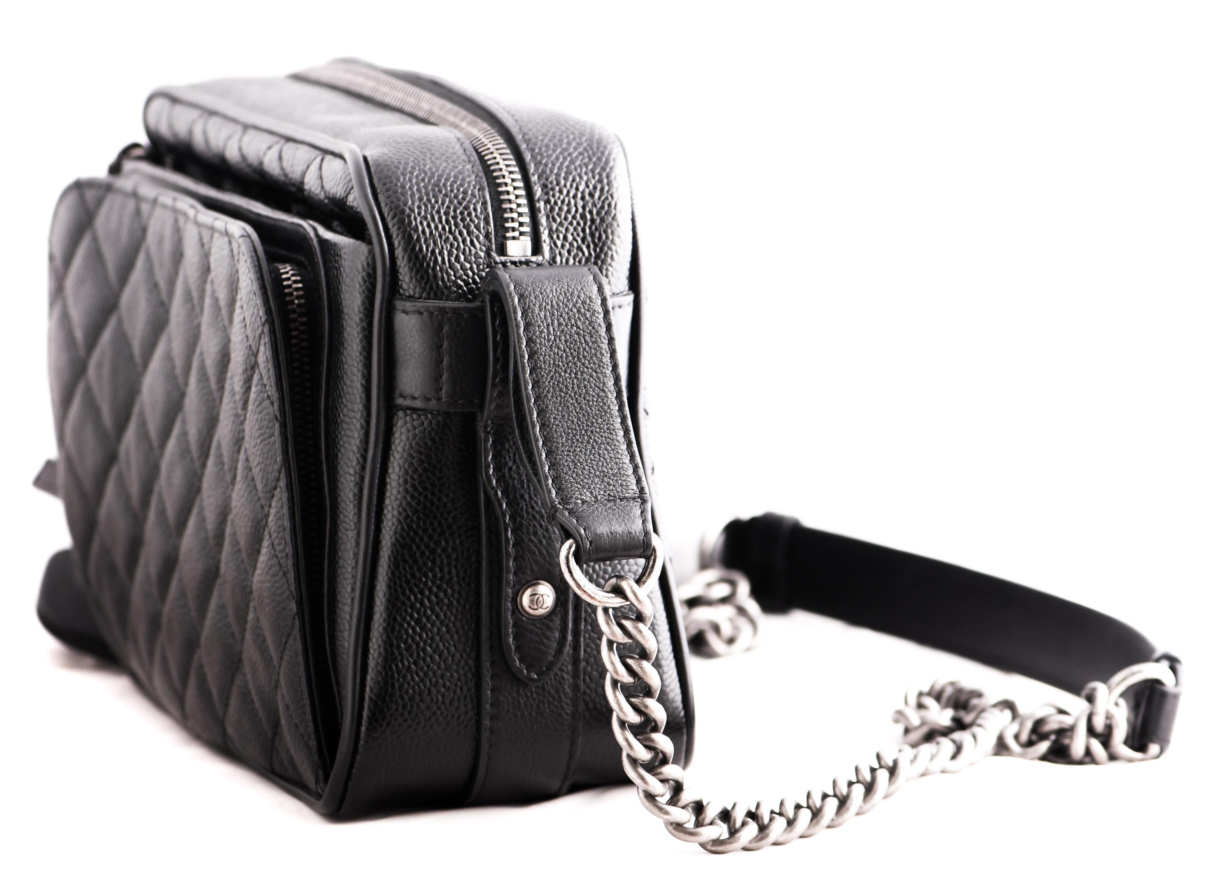 Chanel  chic Affinity camera shoulder bag is finely crafted of luxurious diamond-quilted caviar leather in black. The bag features a leather threaded ruthenium chain shoulder strap, a flat exterior pocket and two front zipper pocket one featuring a