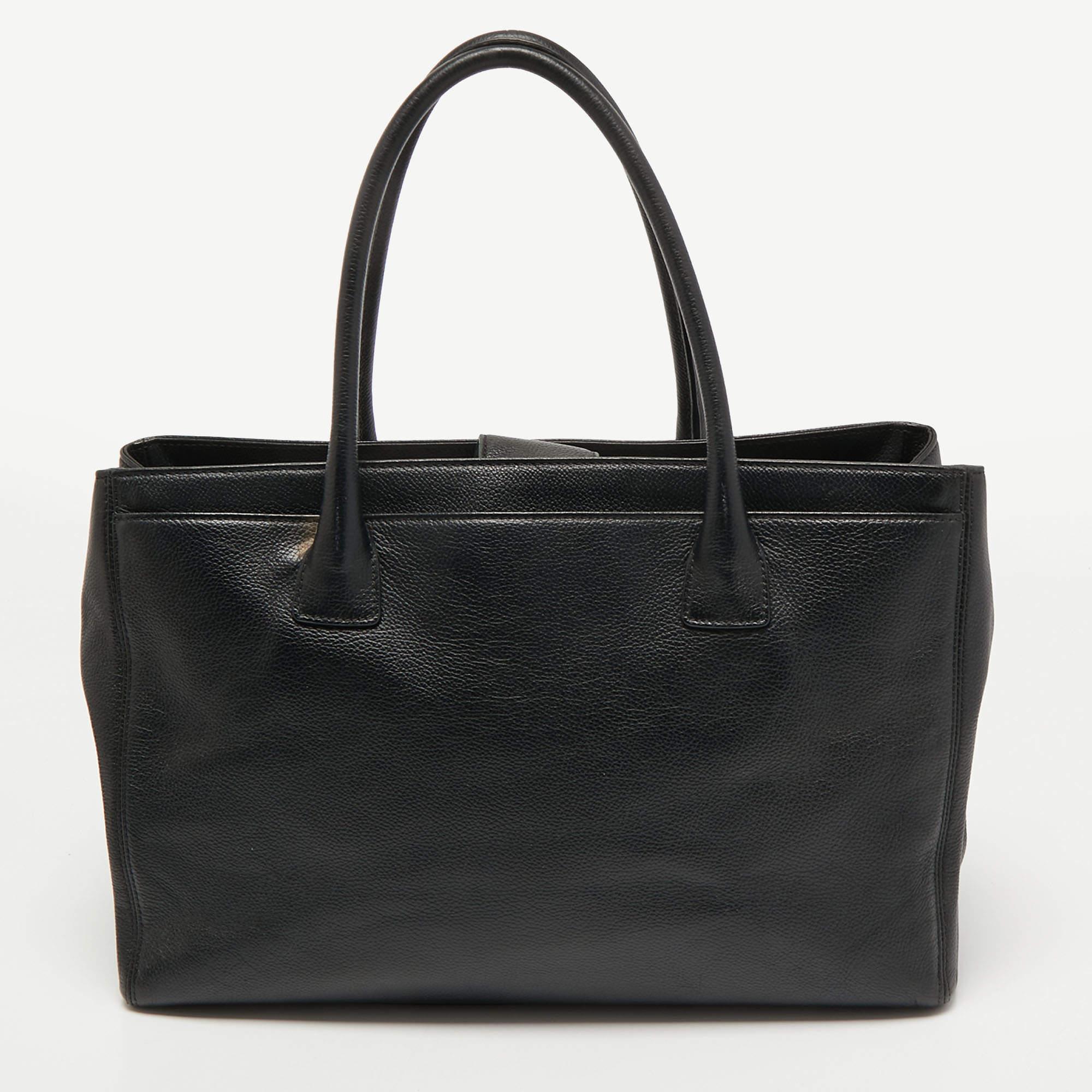 This Cerf tote from Chanel is a perfect blend of function and style. It features a black Caviar leather construction that is enhanced with a metal CC logo on the front and dual top handles. It is equipped with a spacious interior that can easily