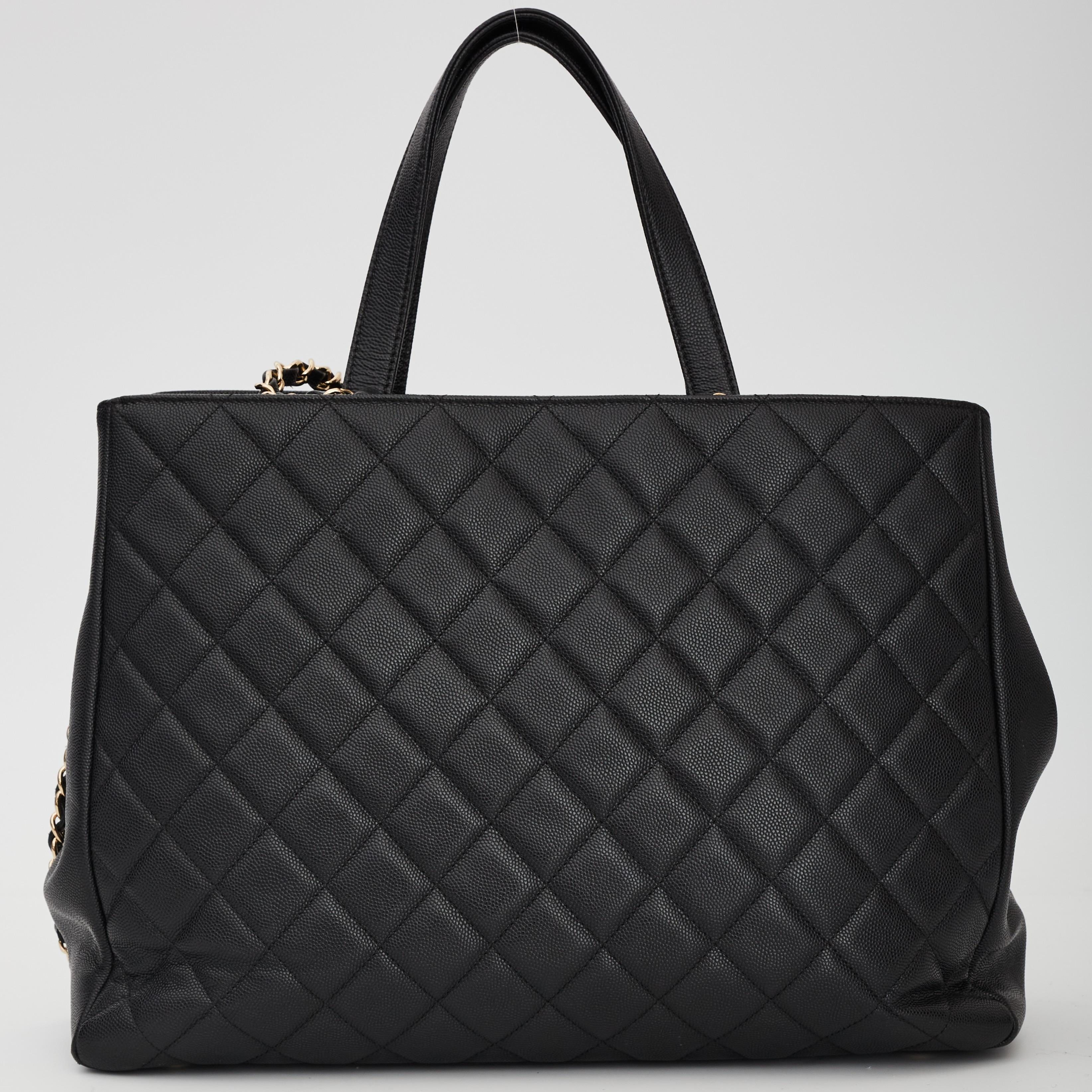 This Chanel shopping tote style bag is made of durable caviar leather in black. The bag features gold hard ware, dual flat leather top handles, an optional shoulder strap, a front CC twist lock closure, a quilted front zip pocket, an open top and a