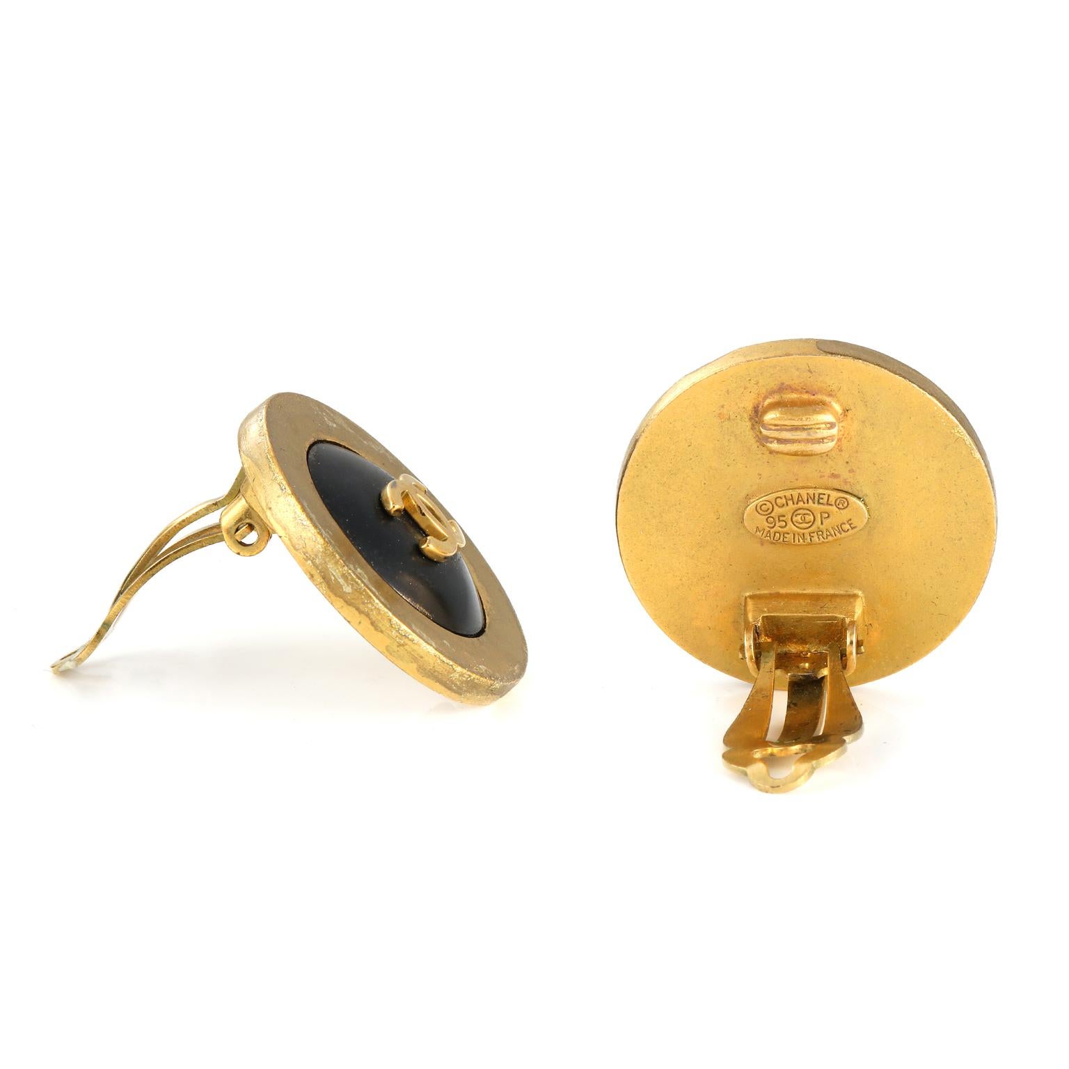 Diese authentischen Chanel Black CC Button Earrings sind in sehr gutem Zustand aus der Spring 1995 Kollektion.  Schwarze Knopfohrringe mit goldener Umrandung und goldenem, ineinandergreifendem CC in der Mitte.  Clipverschluss. Inklusive Tasche oder