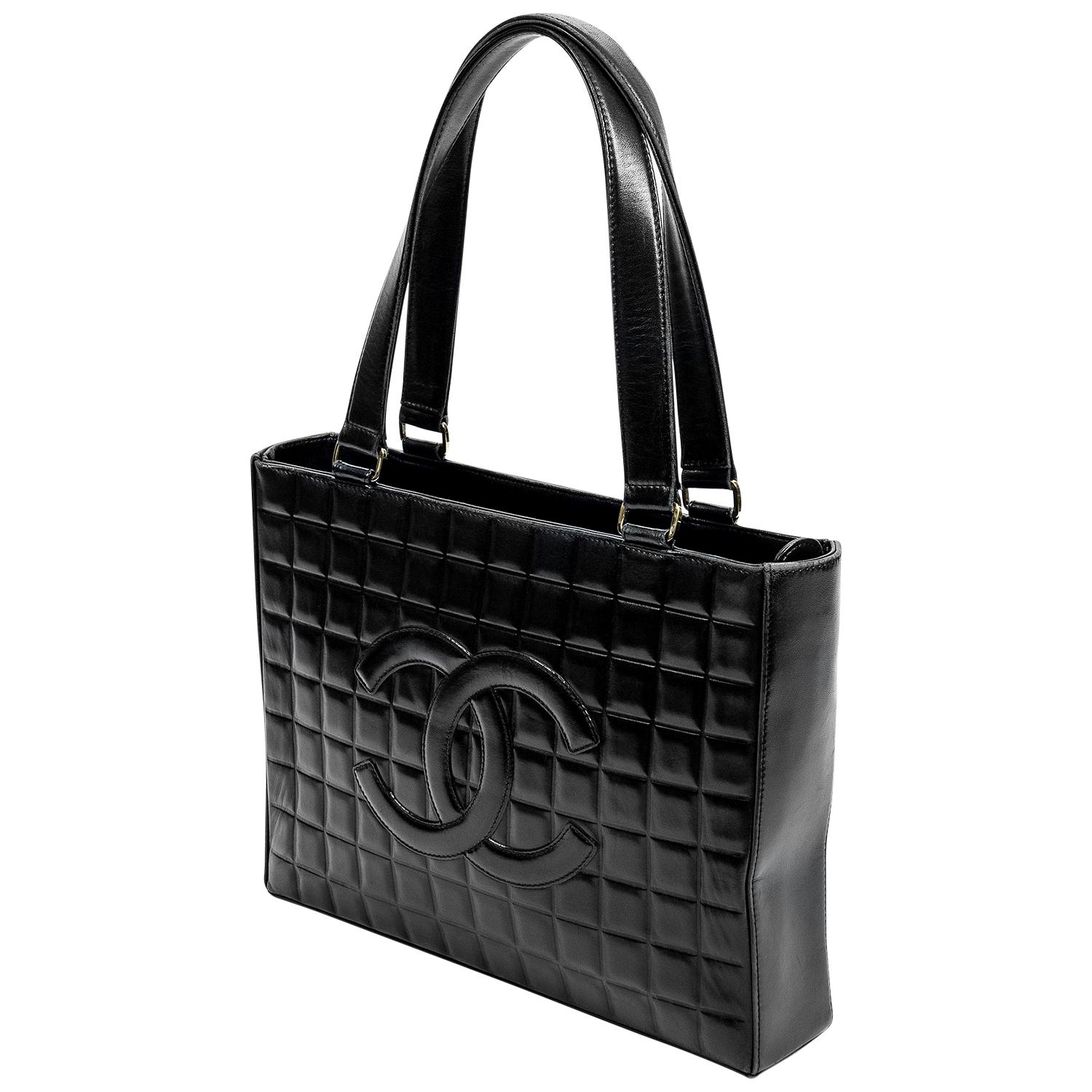 Timeless black chocolate bar shopping tote crafted in black quilted leather with silver-tone hardware, dual shoulder straps, the top zip closure opens up to a grosgrain lining with a single interior pocket. For added practicality, there are