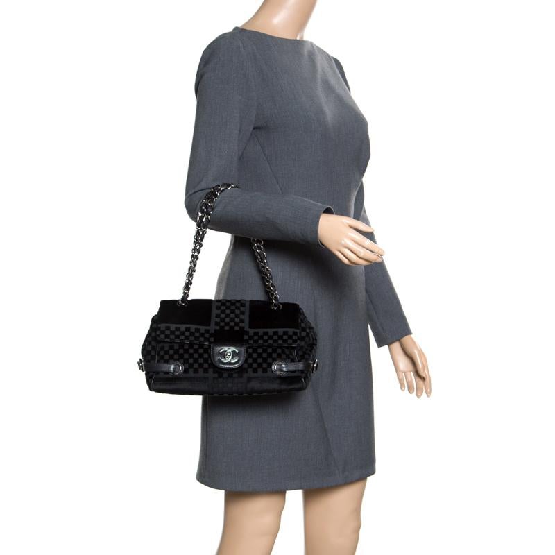 This bowler bag from Chanel is simple in design but high on style. Crafted from check embossed velvet, the black bag features belt detailing on the sides and chain and leather interwoven handles. The CC lock closure opens to a spacious satin lined