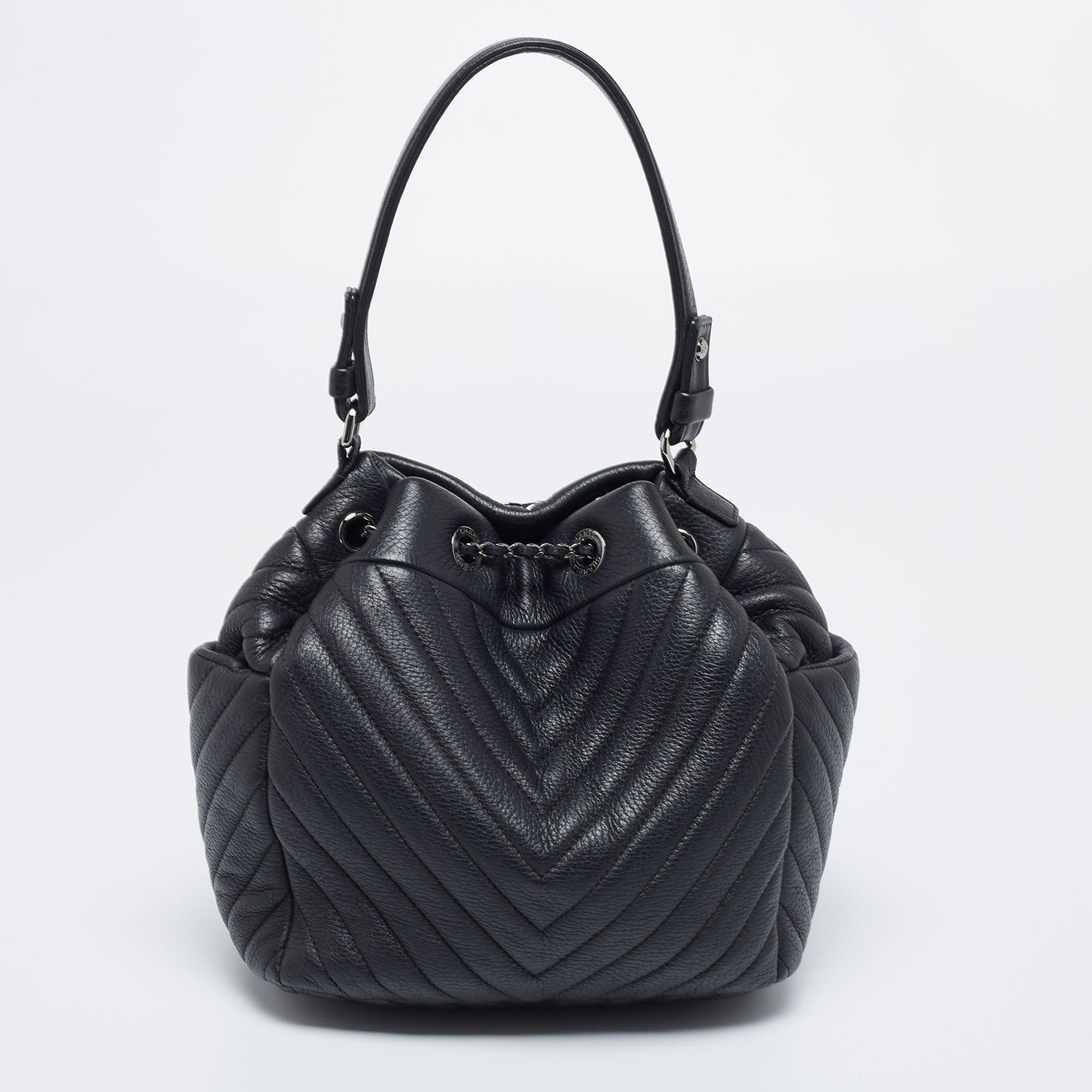 Made to a high quality and brilliant finish, this bucket bag from Chanel will be your companion for years to come. This chevron-quilted leather bag has canvas lining, CC-detailing woven chain drawstring, and a top handle. This accessory will be a