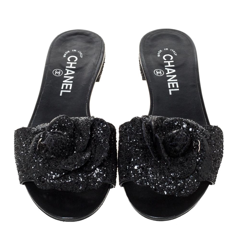 Comfort coupled with fashion creates wonders and these flats slides from Chanel are a true example of that. These black slides are crafted from coarse glitter fabric and feature an open-toe silhouette. They flaunt signature Camellia flowers with the