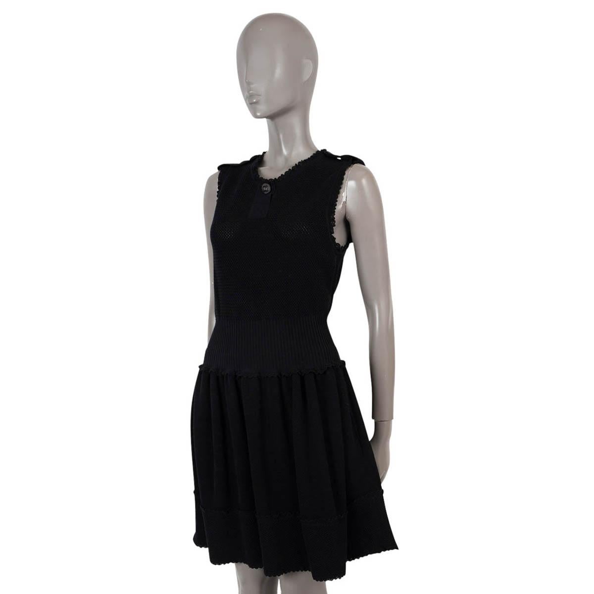 100% authentic Chanel sleeveless knit dress in black cotton (100%). Features scalloped trims, buttoned epaulettes, a silver-tone CC button at the neck, an open knit top, a rib-knit waist and pleated skirt. Has been worn and is in excellent