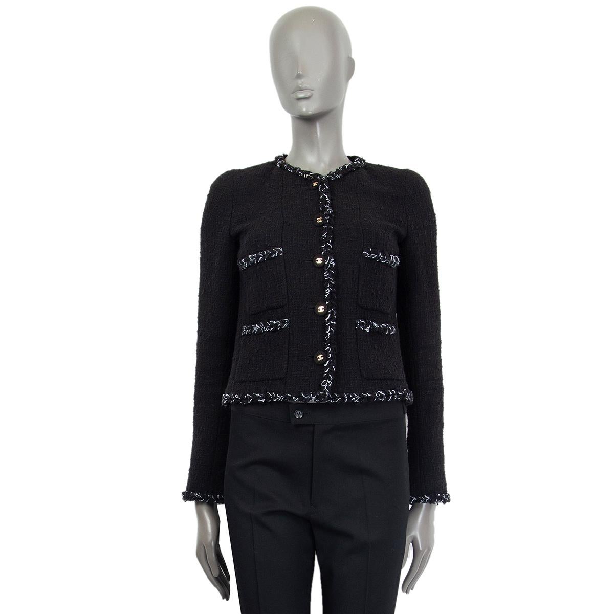 Chanel cropped double-patch jacket in black cotton (62%), acrylic (19%) and polyester (19%) bouclé with white trimming. Lined in black silk (96%) and elastane (4%) with gold-tone chain detail on the bottom. Has been worn and is in excellent