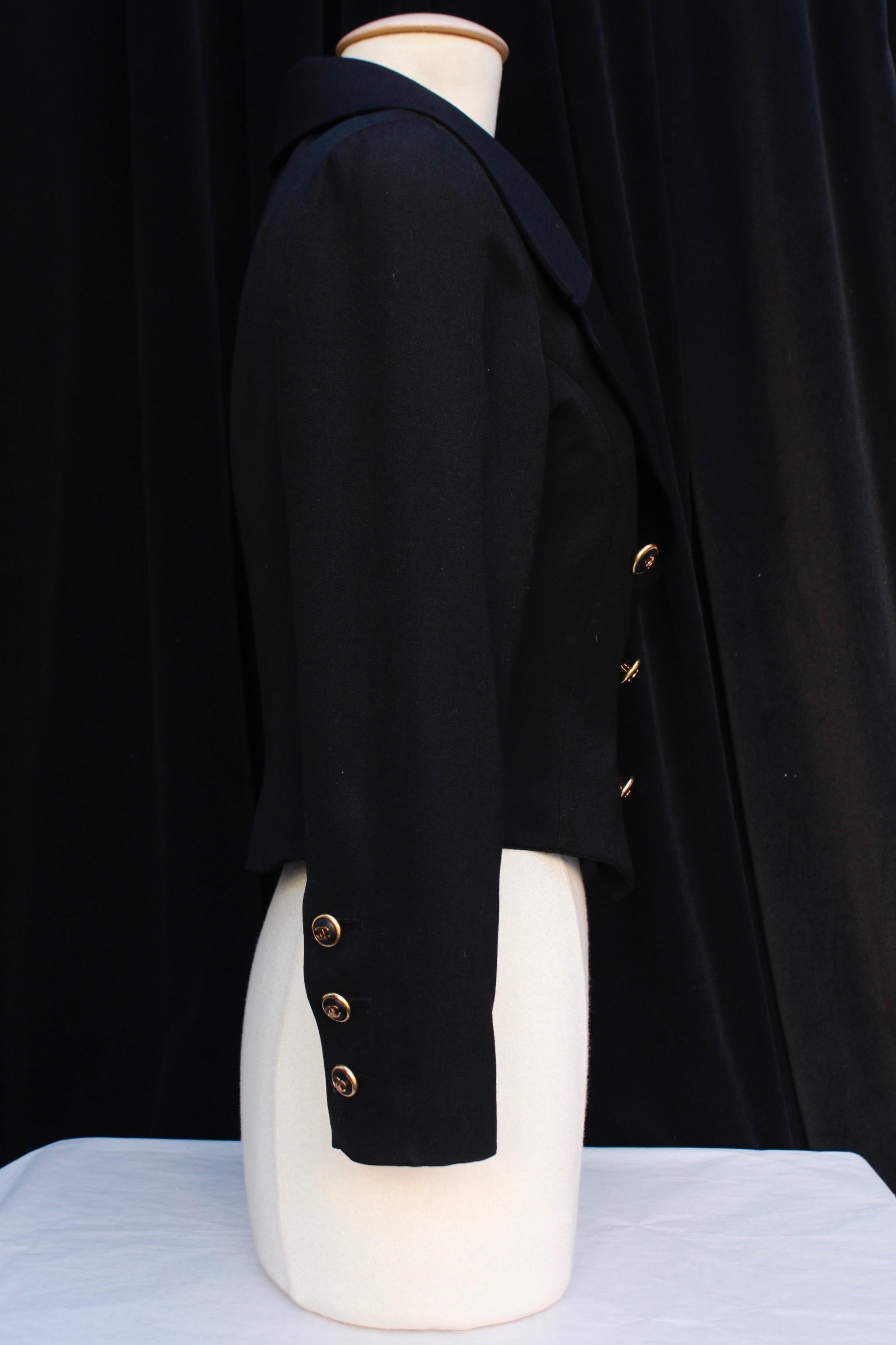 CHANEL BOUTIQUE – Elegant short jacket composed of black cotton blend, with long sleeves and tailored collar. It closes with a double series of gilded metal and black resin buttons with gilded metal CC logo. Black monogrammed silk lining.

No