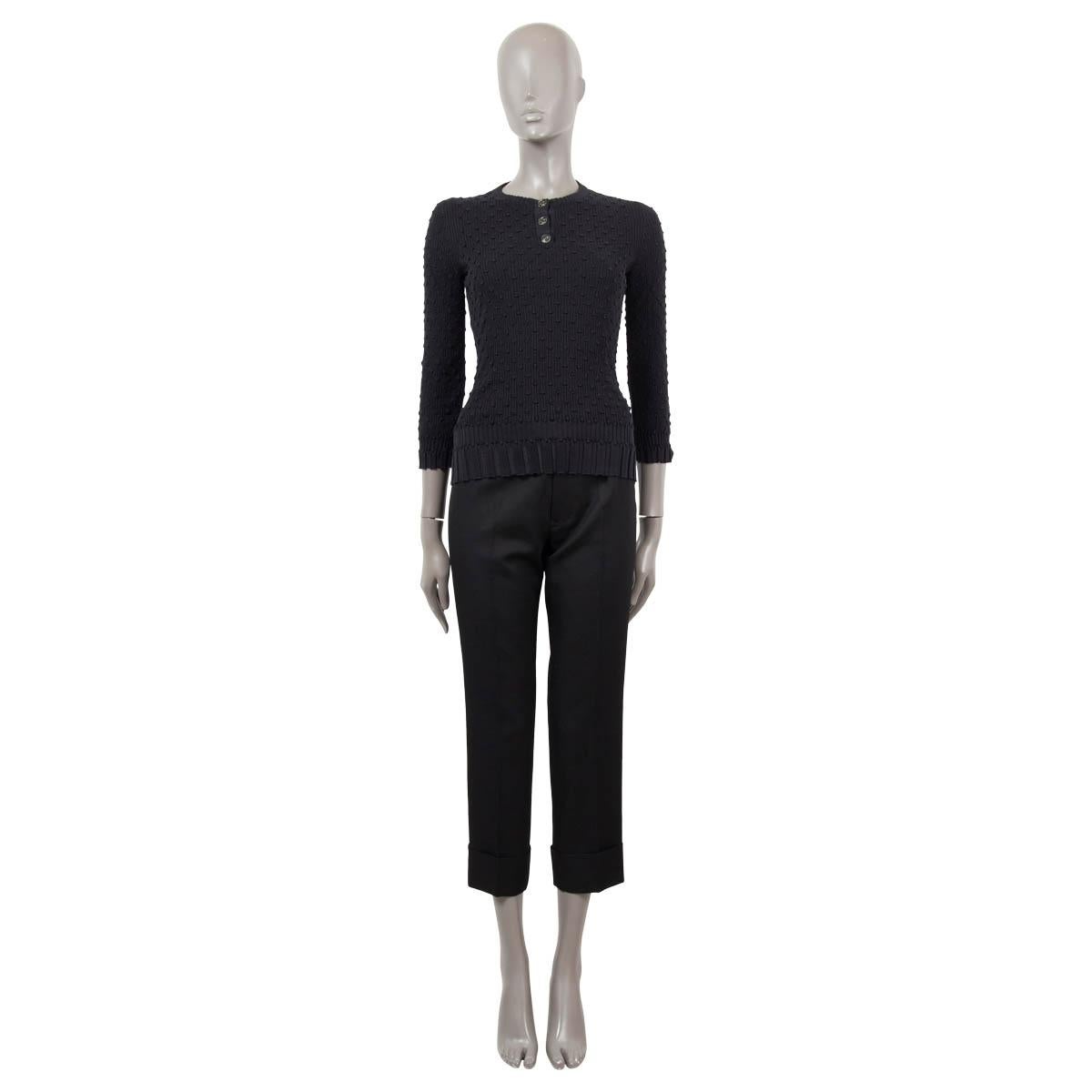 100% authentic Chanel 3/4 sleeve textured henley rib sweater in black cotton (70%) and silk (30%). The design features three celar CC embellished front buttons. Ribbed back. Has been worn and is in excellent condition. 

2018