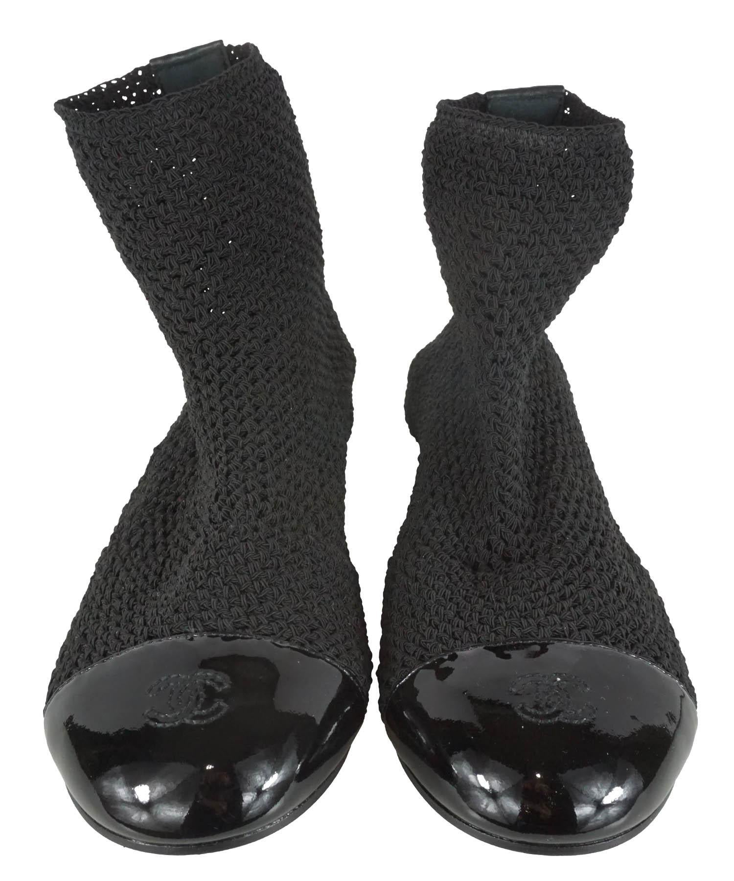 Chanel Sock Ankle Boots are featured in black crocheted stretch fabric with patent leather CC logo round cap toes. Designer size 38. Made in Italy. Excellent condition; boots show no sign of use. Heel height; 0.5