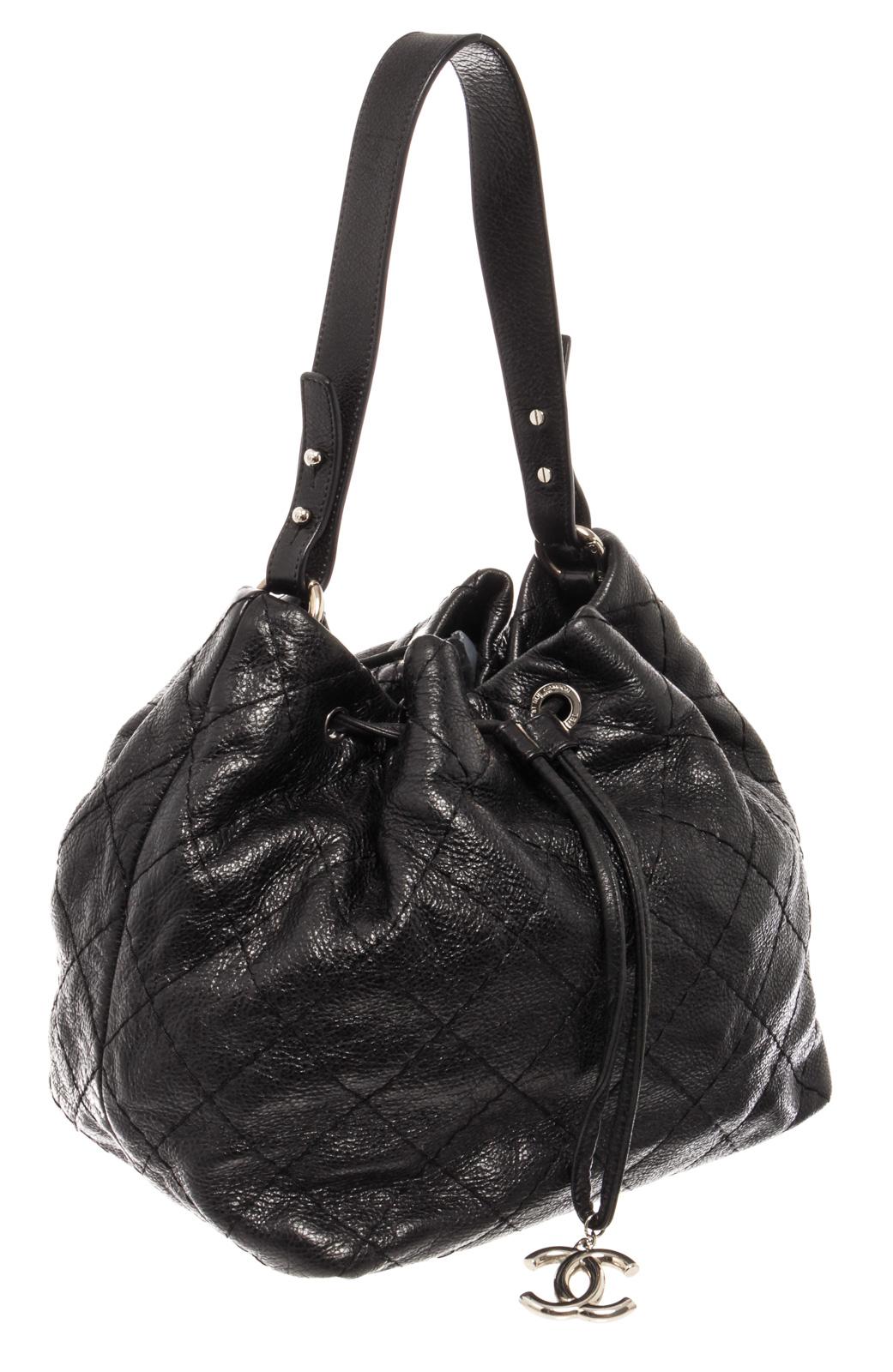 Black diamond-stitched leather Chanel bucket bag with silver-tone hardware, single flat handle, drawstring closure at top with interlocking CC logo charm and black satin lining.

 

220292MSC