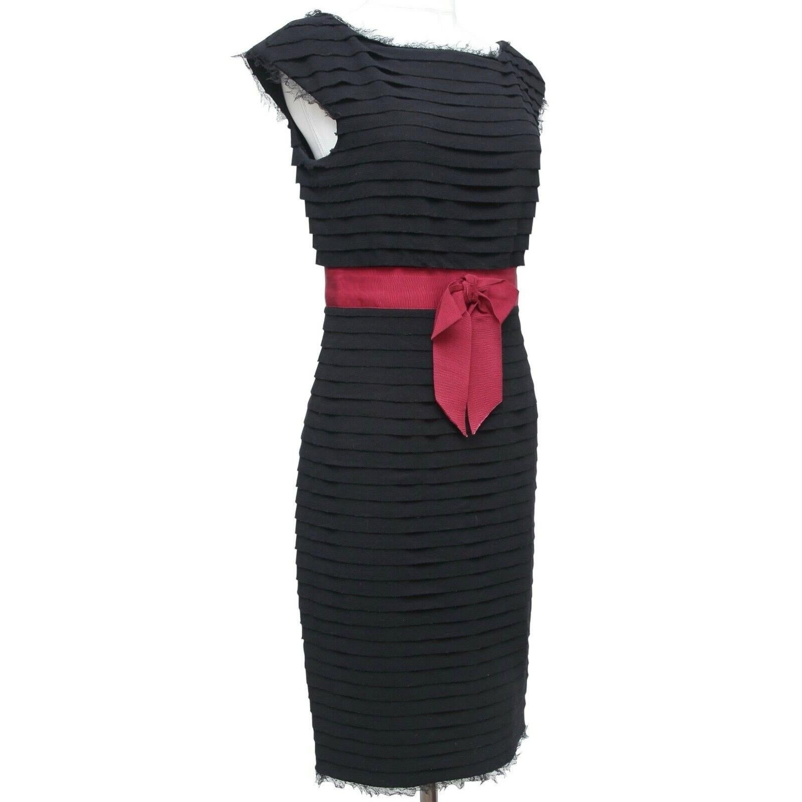 GUARANTEED AUTHENTIC CHANEL BLACK CAP SLEEVE TIERED EVENING DRESS

Details:
• Stunning black wool shift dress tiered detail throughout.
• At waistline is a grosgrain red attached ribbon and bow.
• Lace trim at neckline, arms and hem.
• Bateau