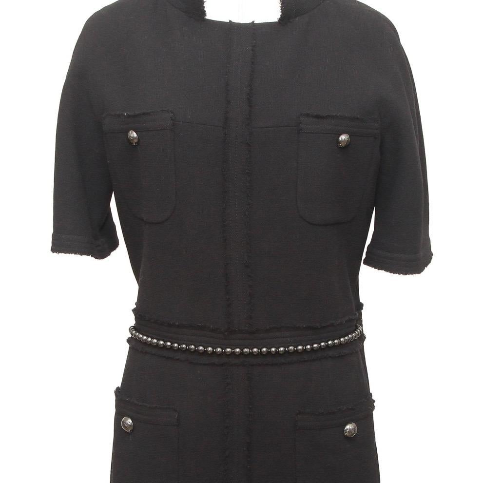 GUARANTEED AUTHENTIC CHANEL 2012 BLACK WOOL BLEND DRESS W/CHAIN BELT

Design:
- Black wool blend style dress.
- Dual patch pockets at chest and hips with gunmetal hammered buttons.
- Mock collar.
- Raw edge fringe accents at edges down center and