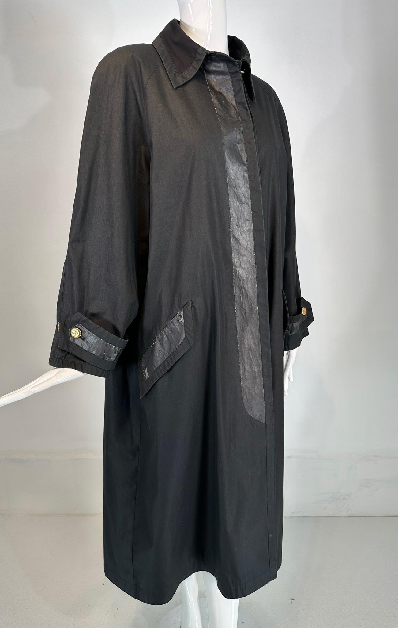 Chanel black cotton blend, duster style distressed vintage raincoat from the 1980s marked size 40. 
Black cotton blend raincoat, duster style, with a wing collar, long raglan sleeves with strap & button cuffs. The coat has a placket front with